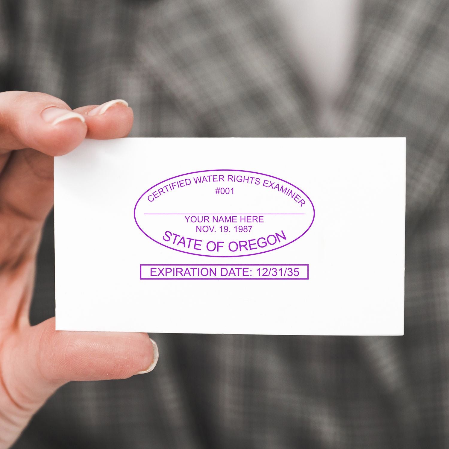 Hand holding a business card with a purple Certified Water Rights Examiner stamp from the State of Oregon.