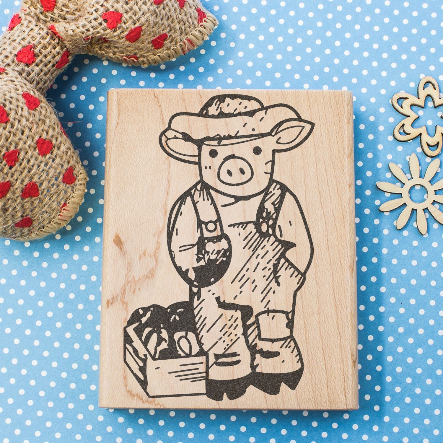 Wooden stamp with cute pig farmer illustration on blue polka dot background, rustic farmhouse craft decor.
