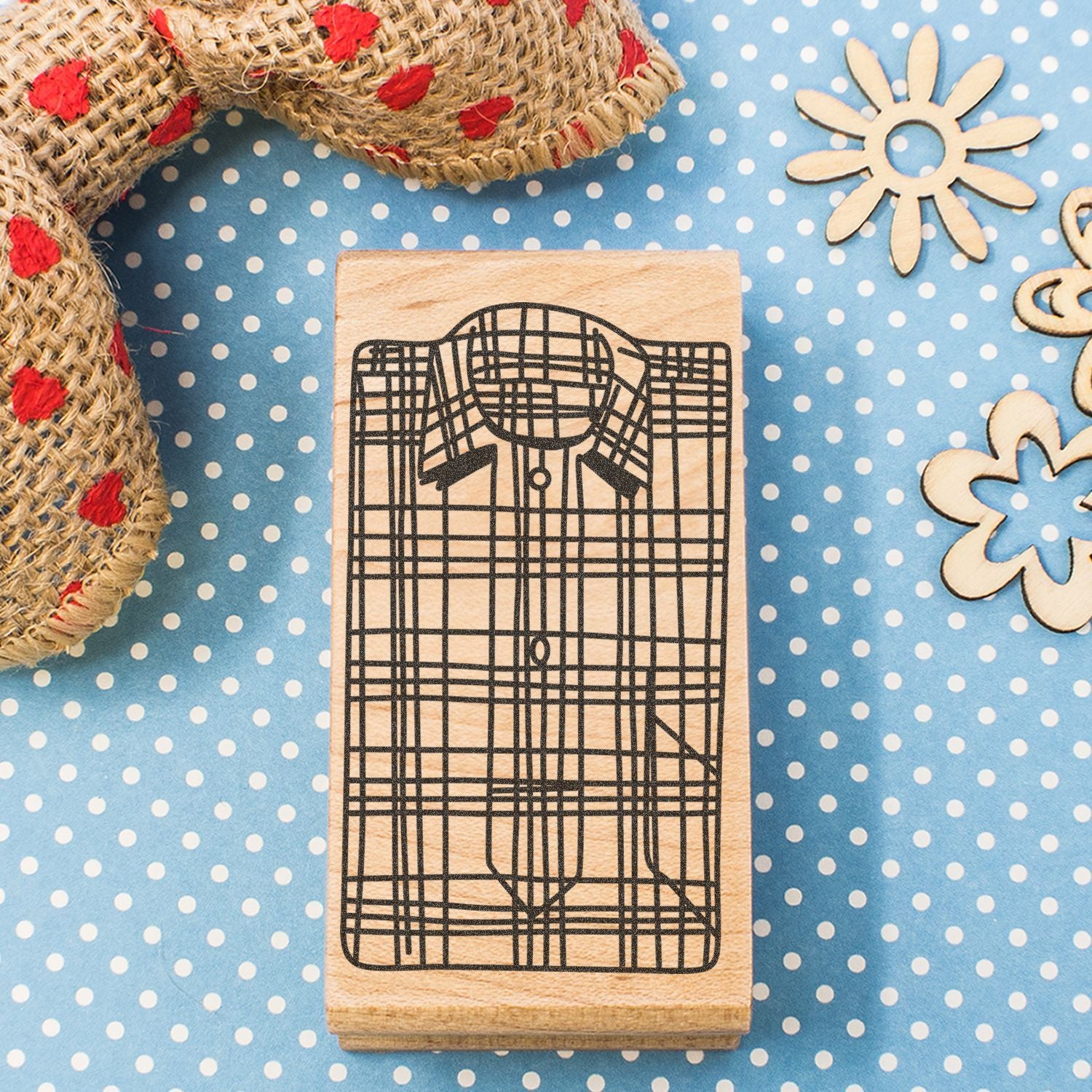 Wooden plaid shirt rubber stamp on blue polka dot background with rustic rope and floral craft decorations.