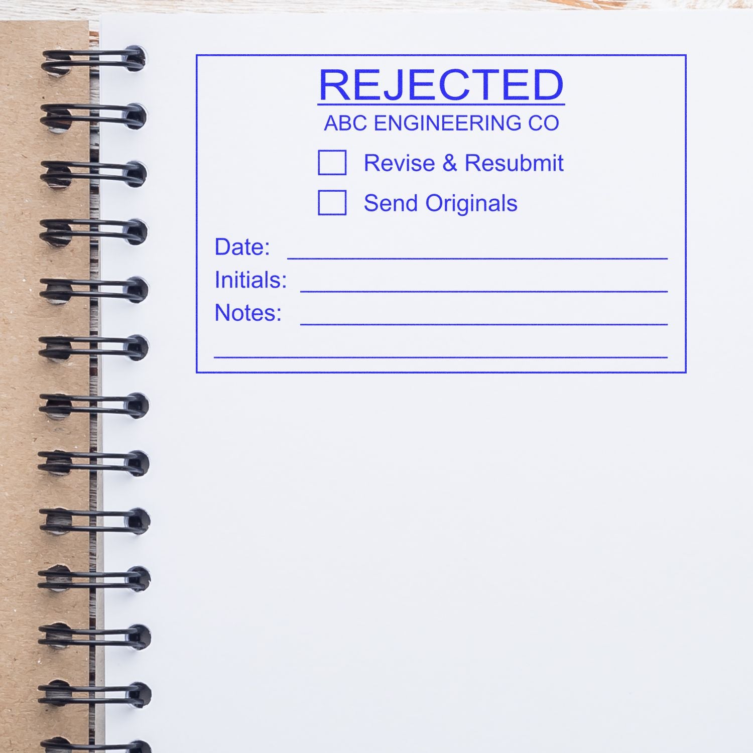 Rejected engineering document stamp on spiral notebook page with revise and resubmit notes.