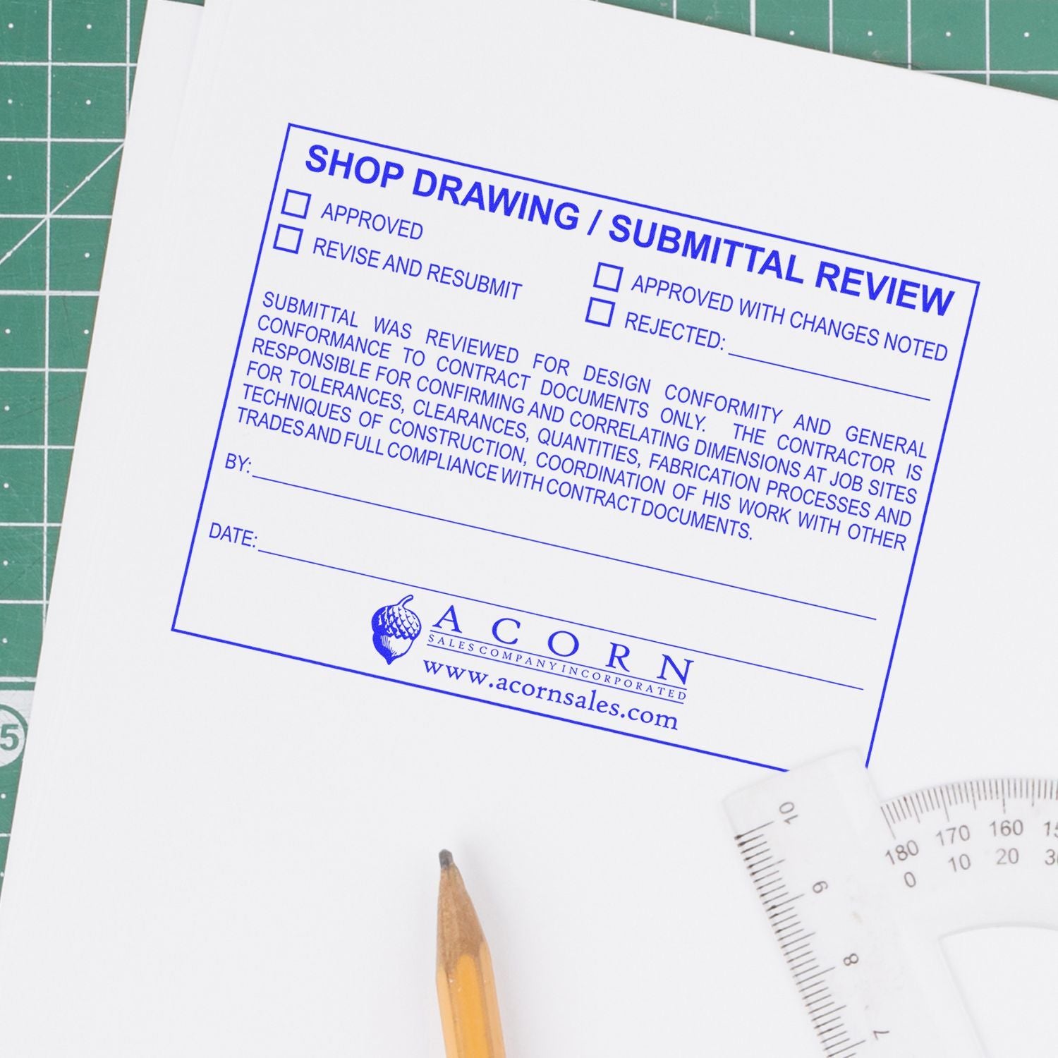 Shop drawing submittal review form on drafting paper with pencil and ruler on cutting mat, construction blueprint approval document.