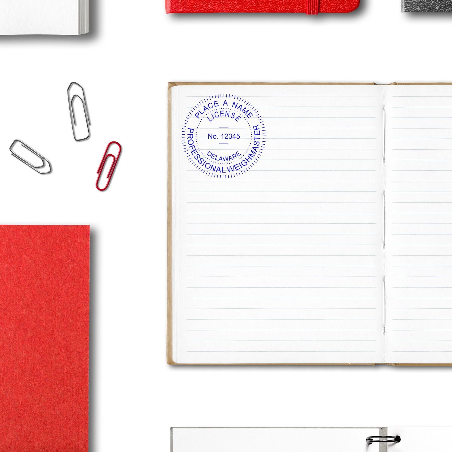 Open lined notebook with professional weighmaster license stamp, paper clips, and red office stationery on white background