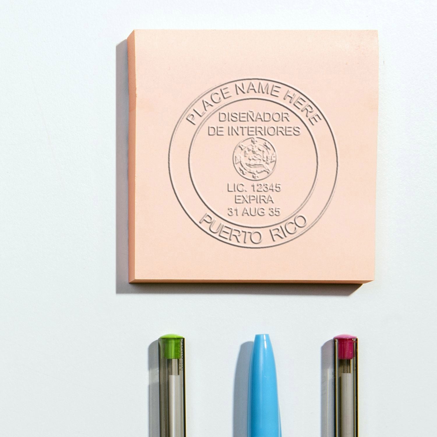 Interior designer license plaque in Puerto Rico with pens on a white wall.