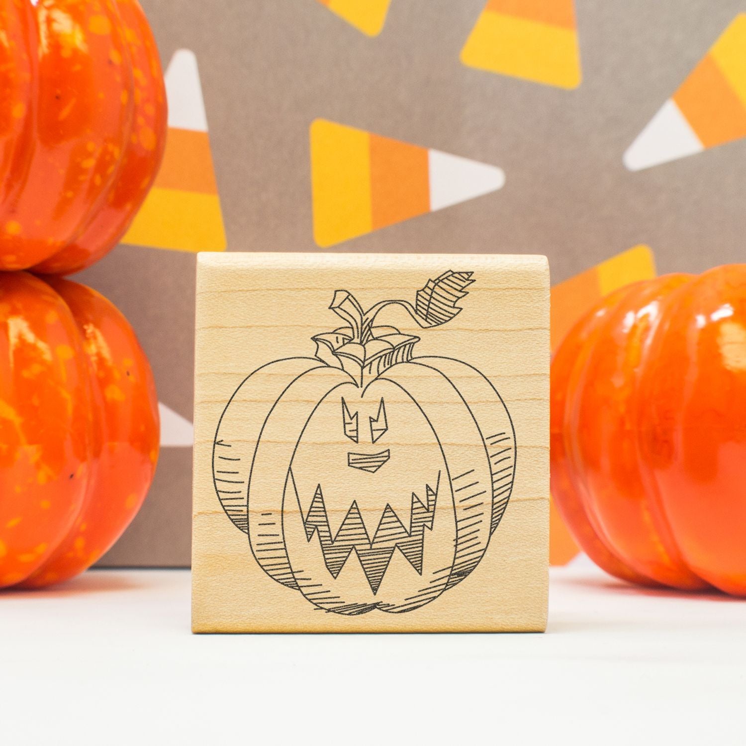 Halloween pumpkin stamp on a wooden block with orange pumpkin decorations and festive autumn background