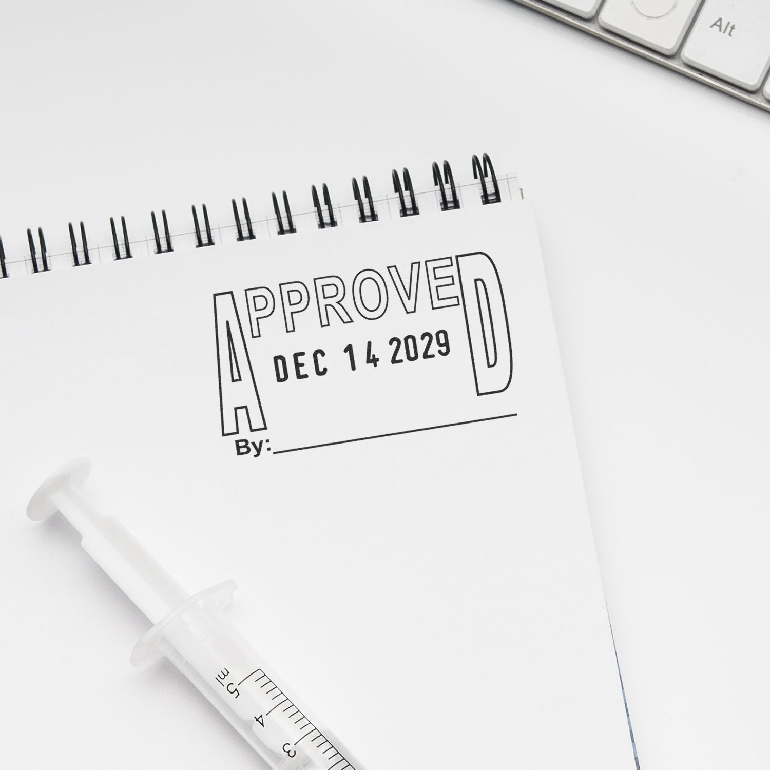 Approved date stamp on notebook with syringe on white background, medical approval concept.