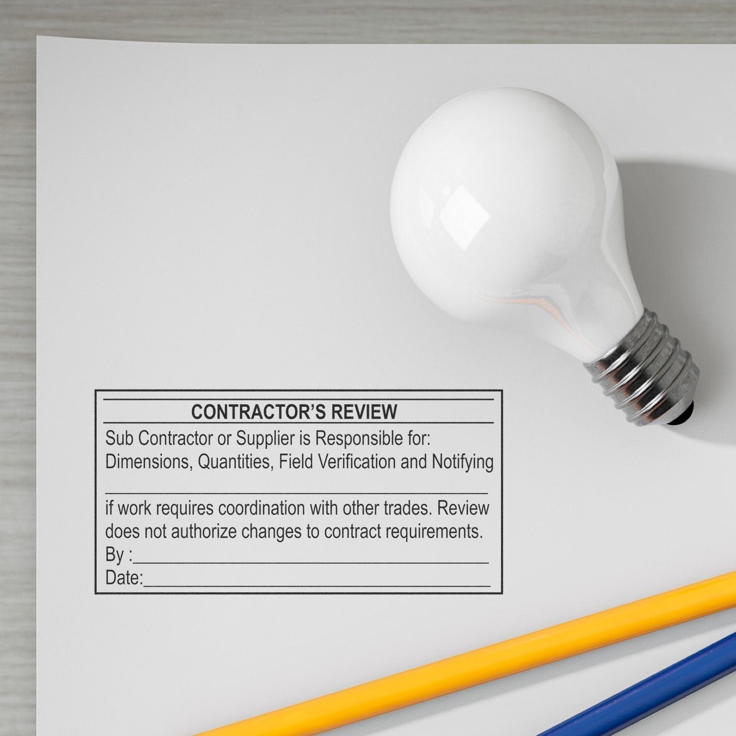 Contractors review form with light bulb and pencils on desk, construction planning and project coordination document.