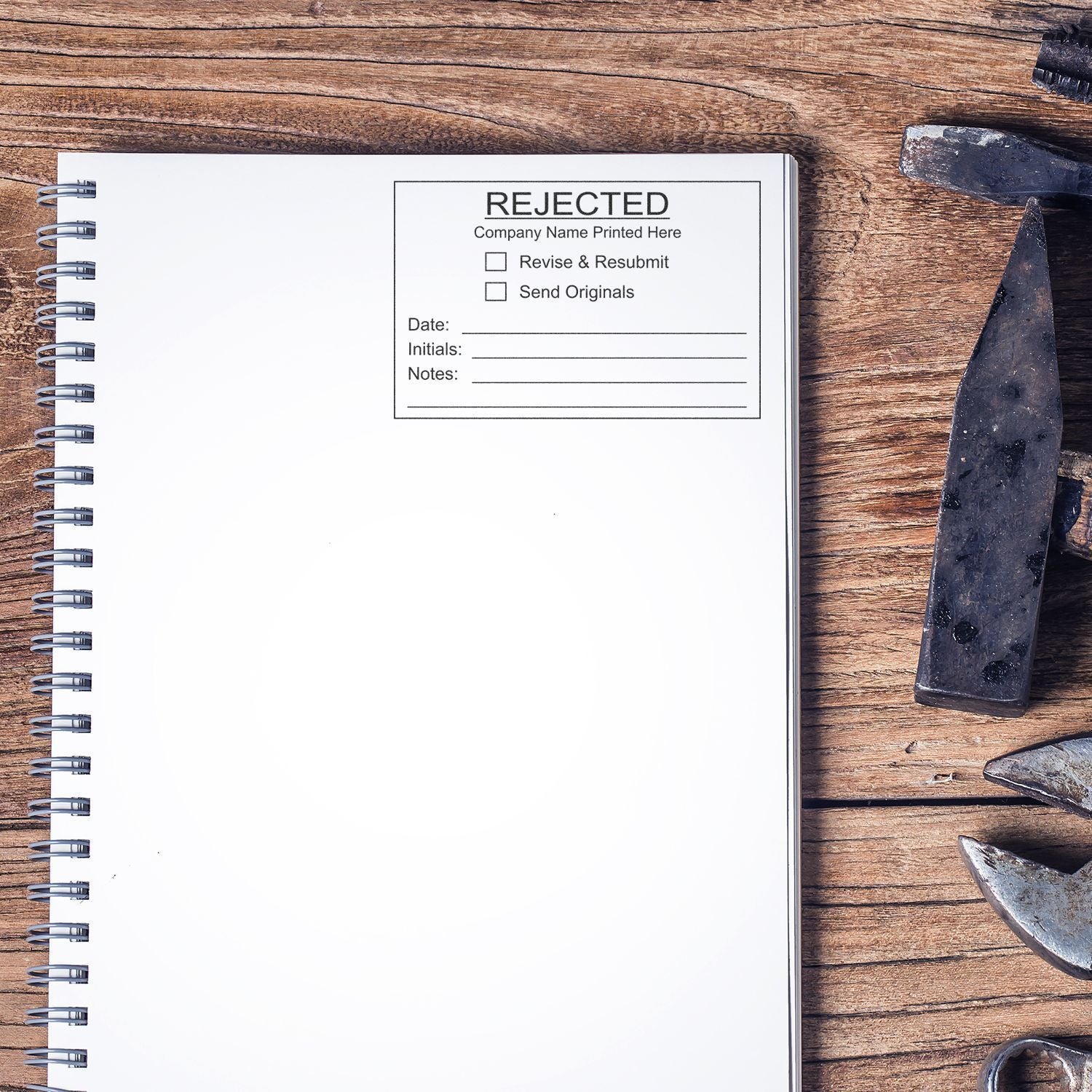 Rejected approval stamp on blank spiral notebook on rustic wooden desk with metal tools, concept of business rejection and resubmission.