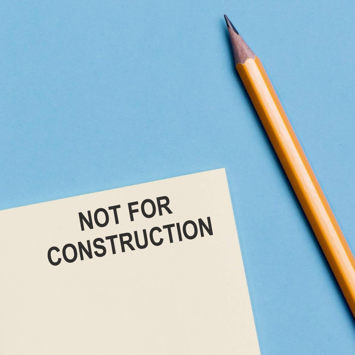 Not for construction note beside a pencil on a blue background.