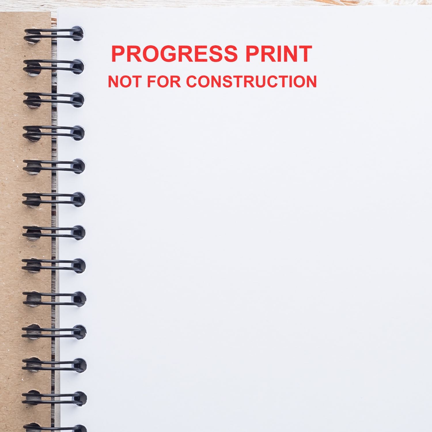Spiral notebook page with red Progress Print Not for Construction stamp on a blank architectural drawing sheet.
