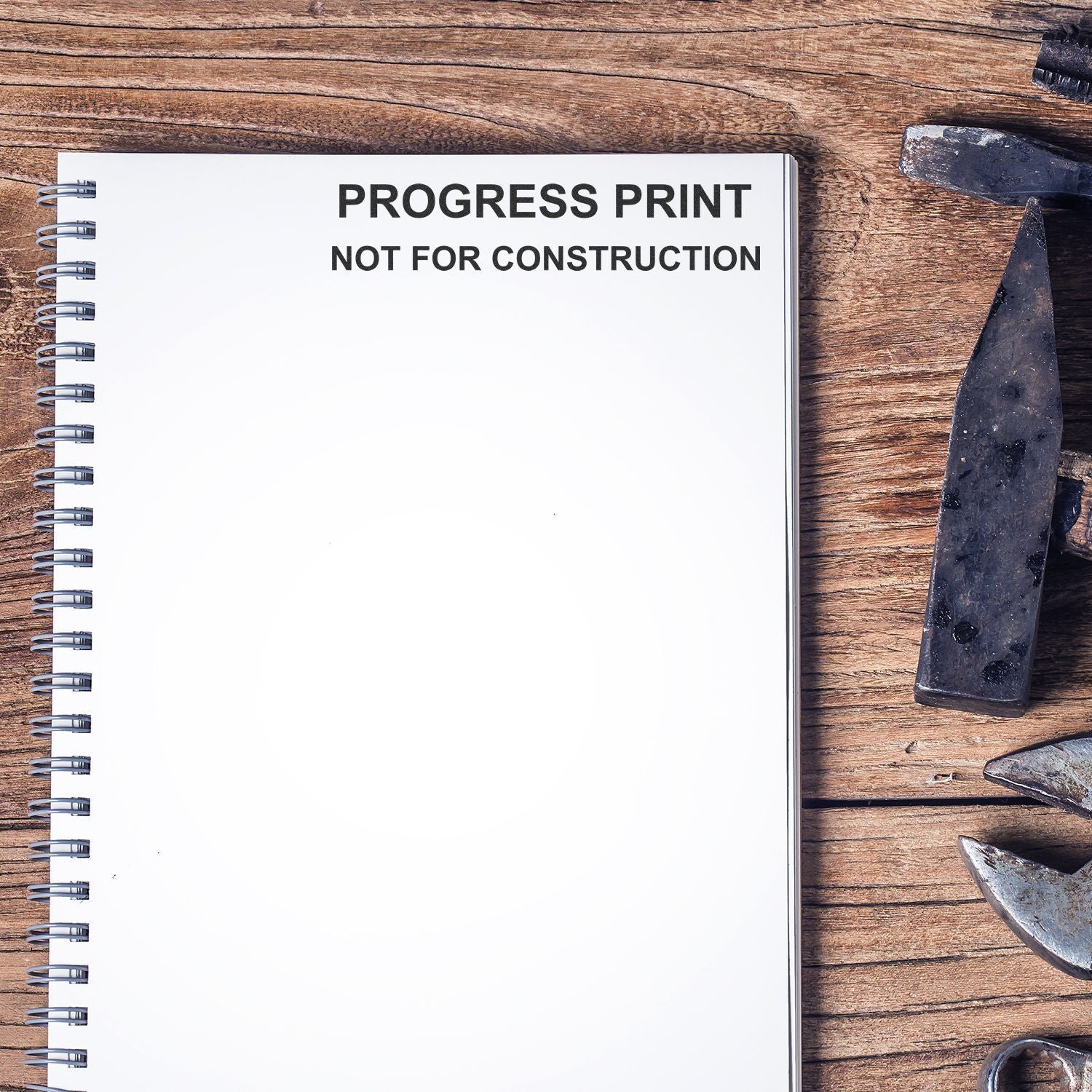 Progress print notebook on wooden table with construction tools, labeled Not for Construction near blueprint and nail materials.