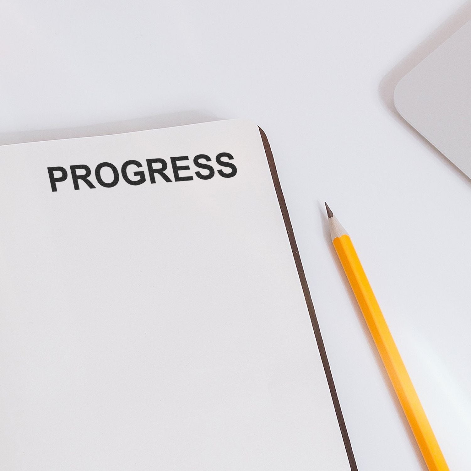 Minimalist notebook page with the word PROGRESS and a yellow pencil on a clean white background, symbolizing productivity and goal tracking.