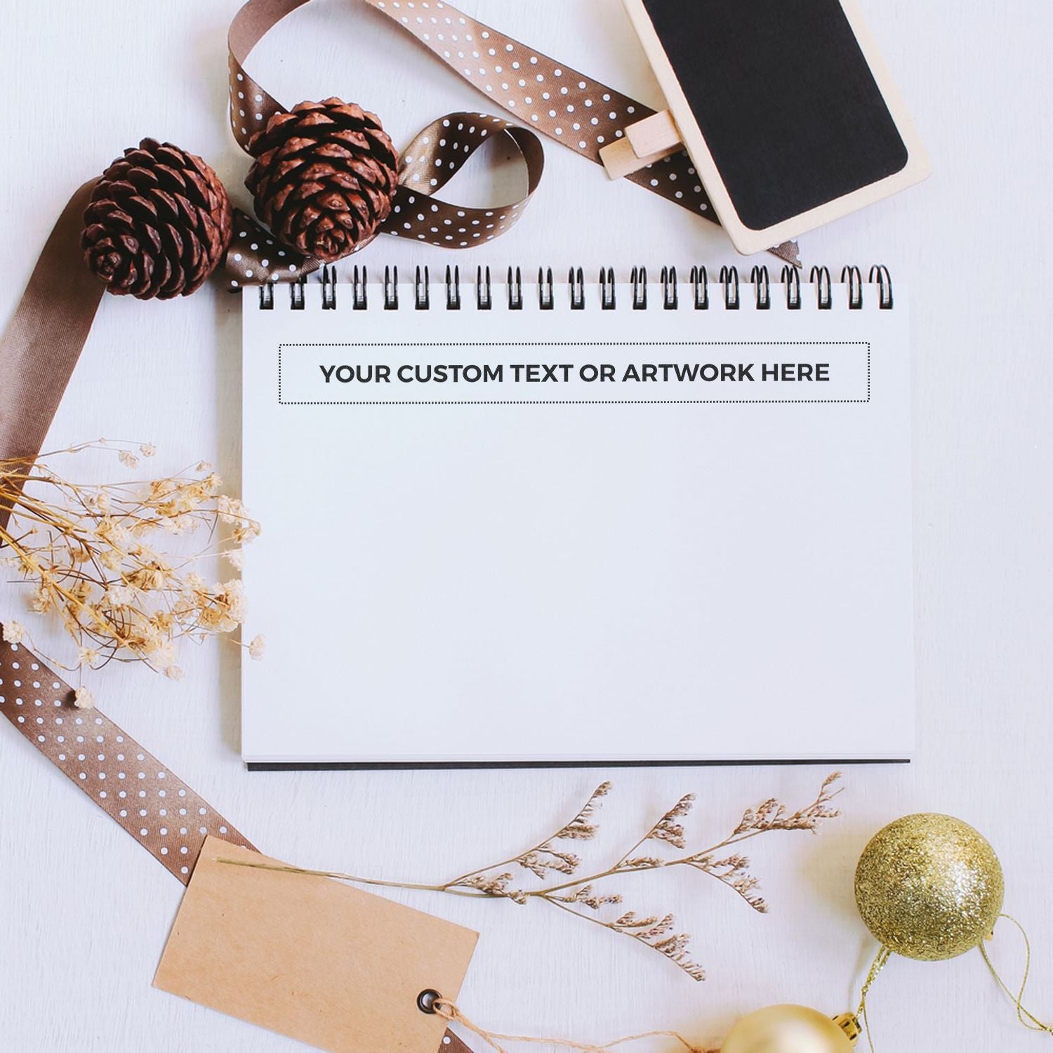 Holiday flat lay with blank note card and gold ornaments, pinecones, and ribboncustom greeting or gift text space.