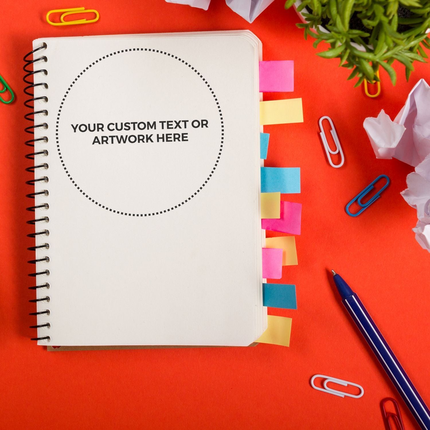 Customizable notebook mockup with text placeholder on open spiral journal, stationery supplies on red background for design layout.