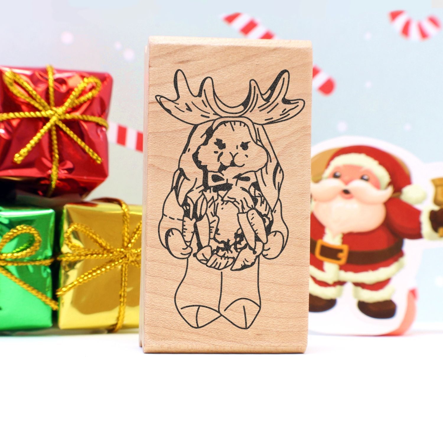 Christmas wooden stamp with cute reindeer Santa design, surrounded by festive gift boxes and holiday decorations