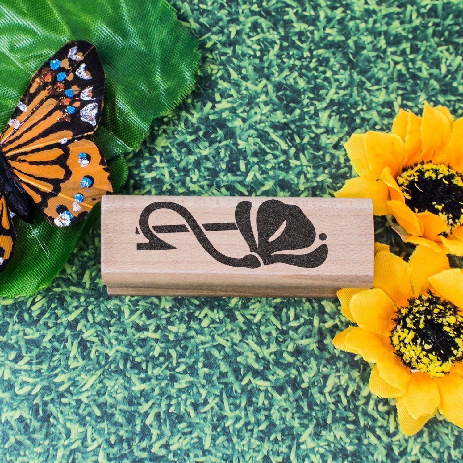Wooden butterfly stamp surrounded by sunflower and butterfly decorations on a green background