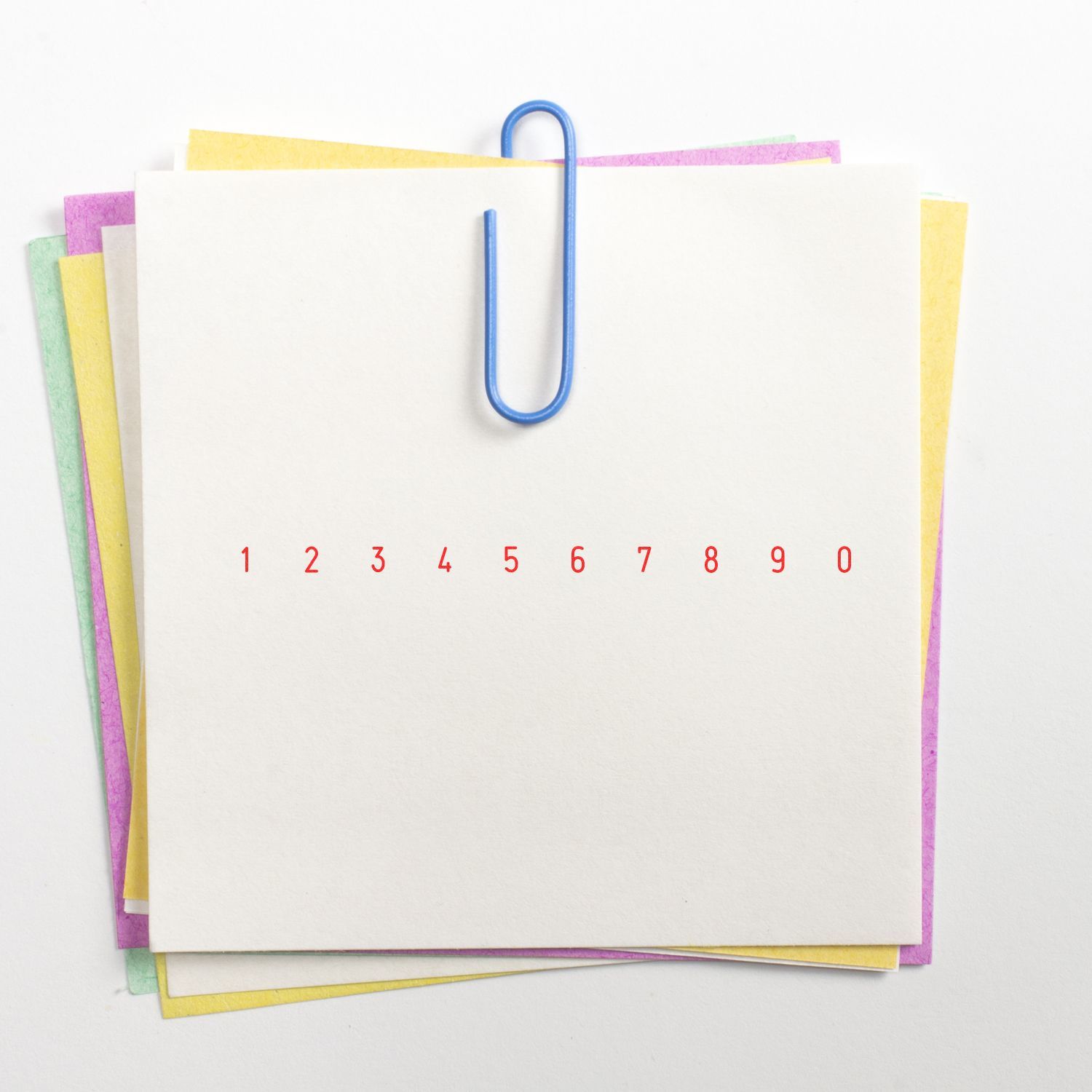Colorful stack of blank sticky notes clipped with a blue paperclip, featuring red numbers 1 to 0 on a white background.