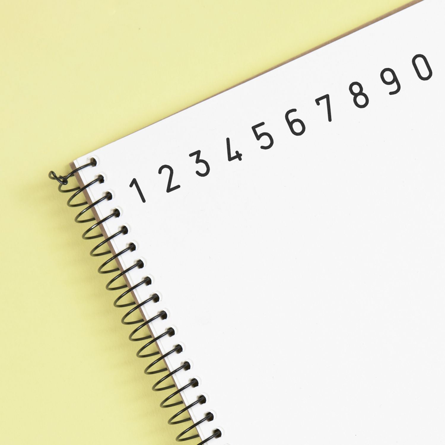 Spiral notebook with numbered tabs 1 to 9 and blank white page on yellow background.