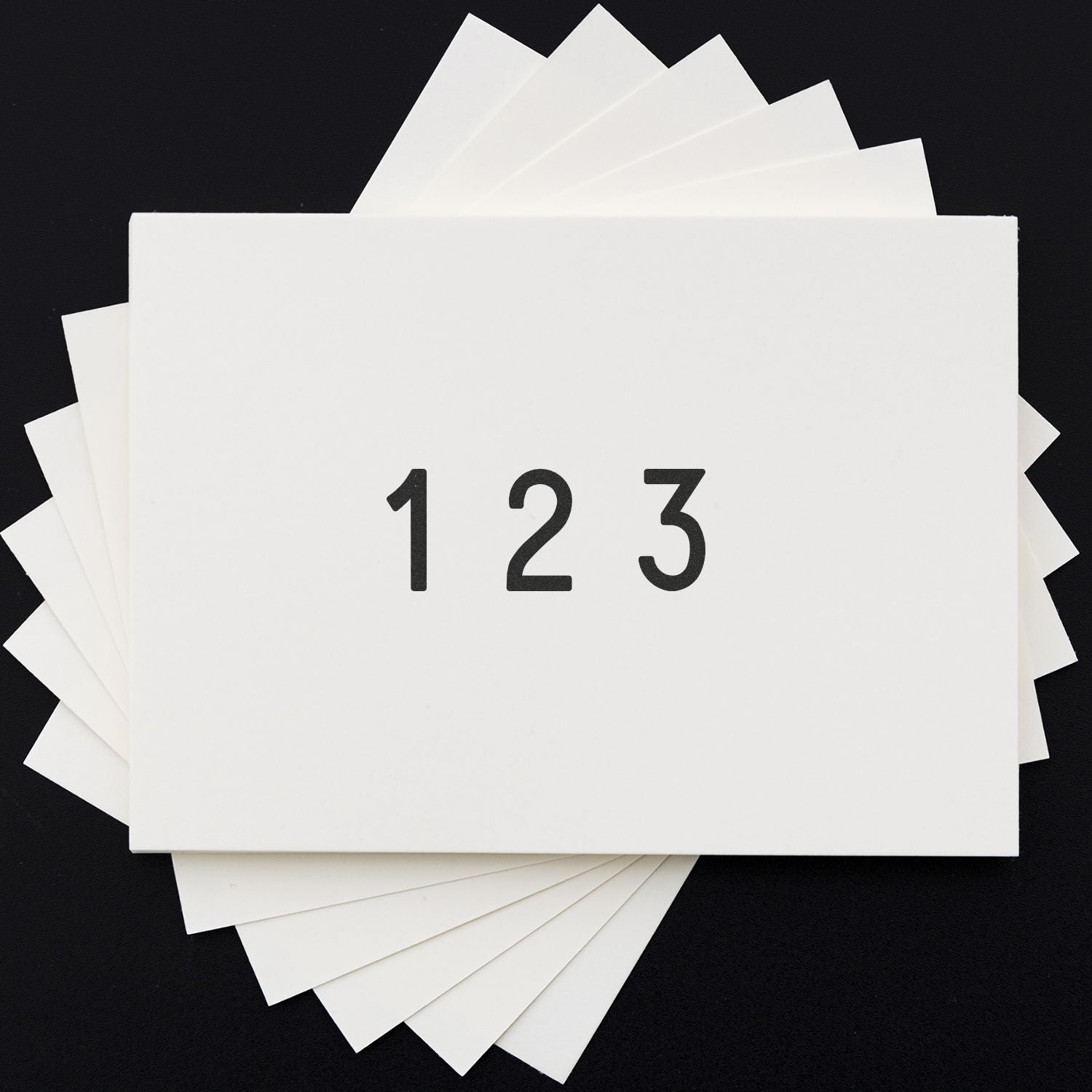Stack of white blank paper sheets with 123 printed on top against a black background.