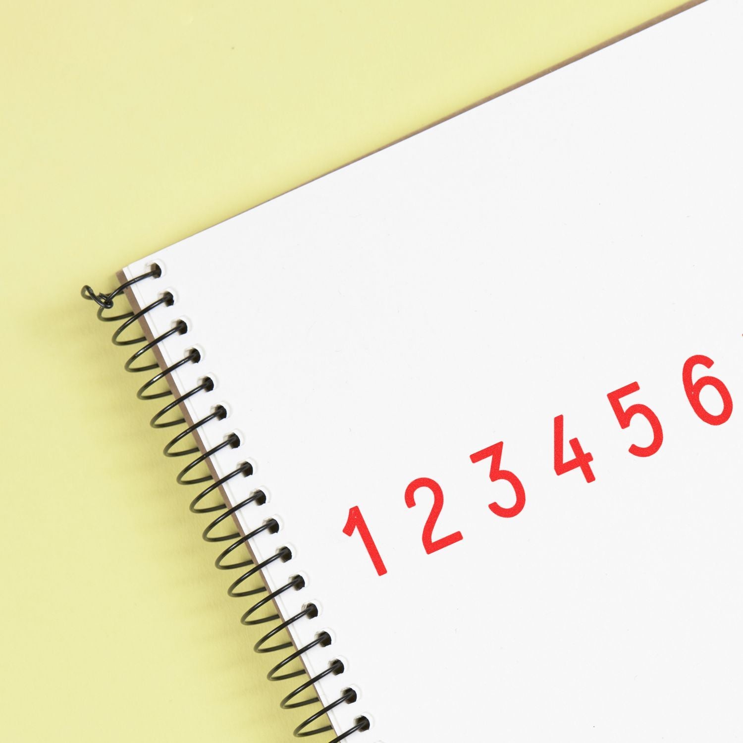 Spiral notebook with red numbers 1 to 6 on a blank white page against a yellow background.