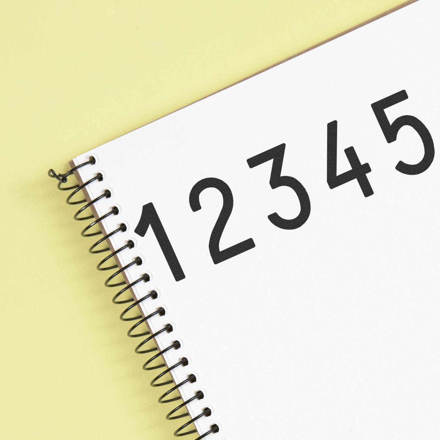 Spiral notebook with large black numbers 1 2 3 4 5 on a yellow background.