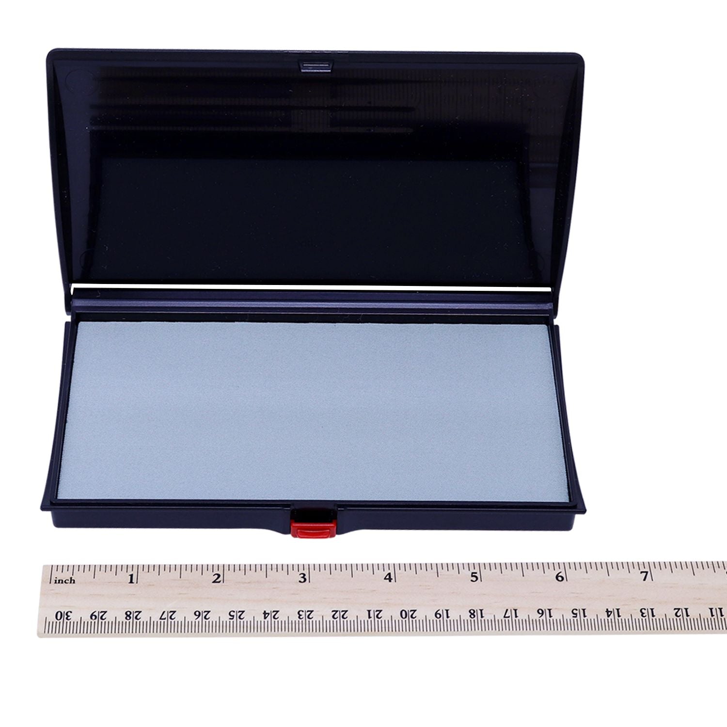 Open black makeup compact with mirror and silver cosmetic pan, shown with ruler for size reference
