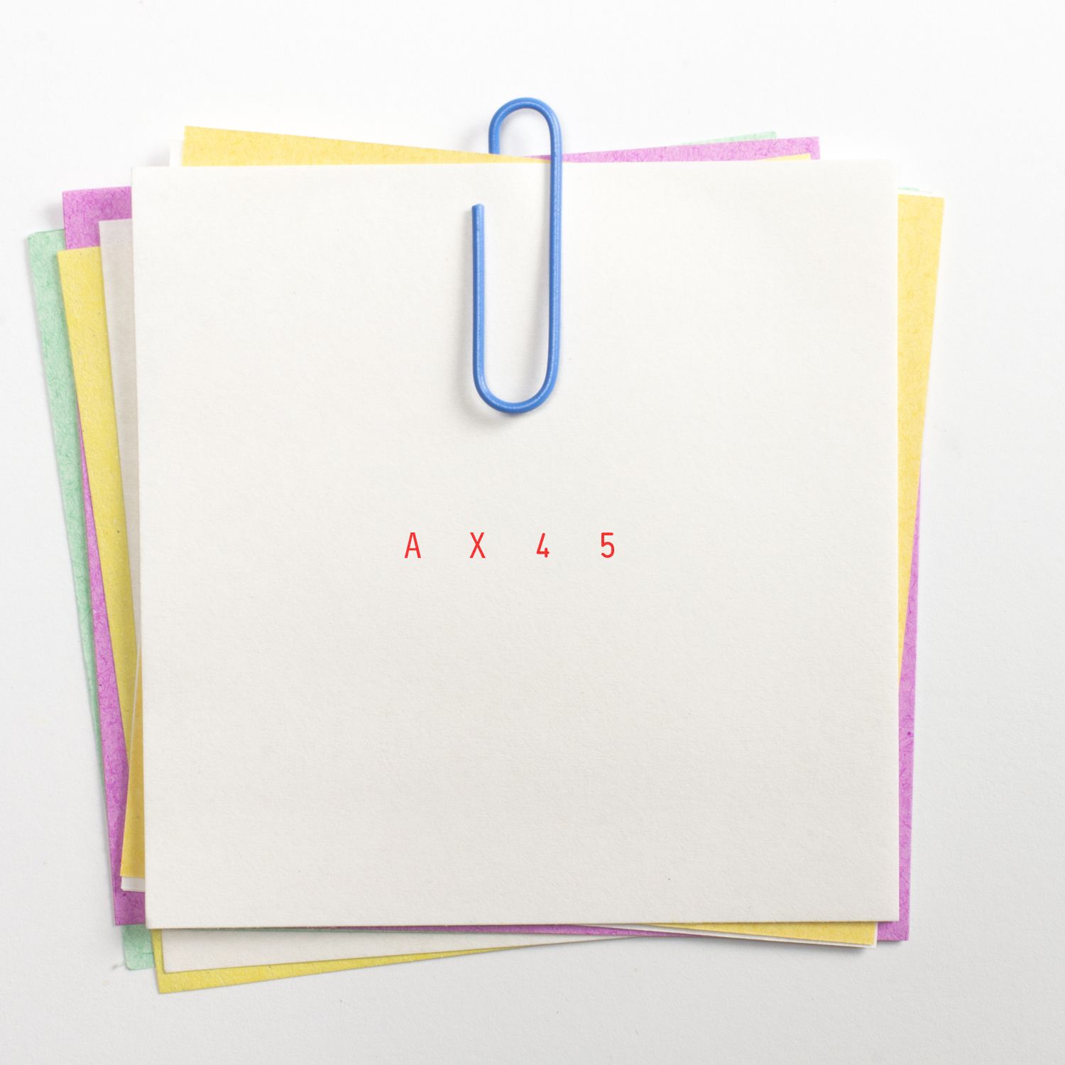 Blank stacked paper sheets clipped with blue paperclip, labeled AX45, office document background.