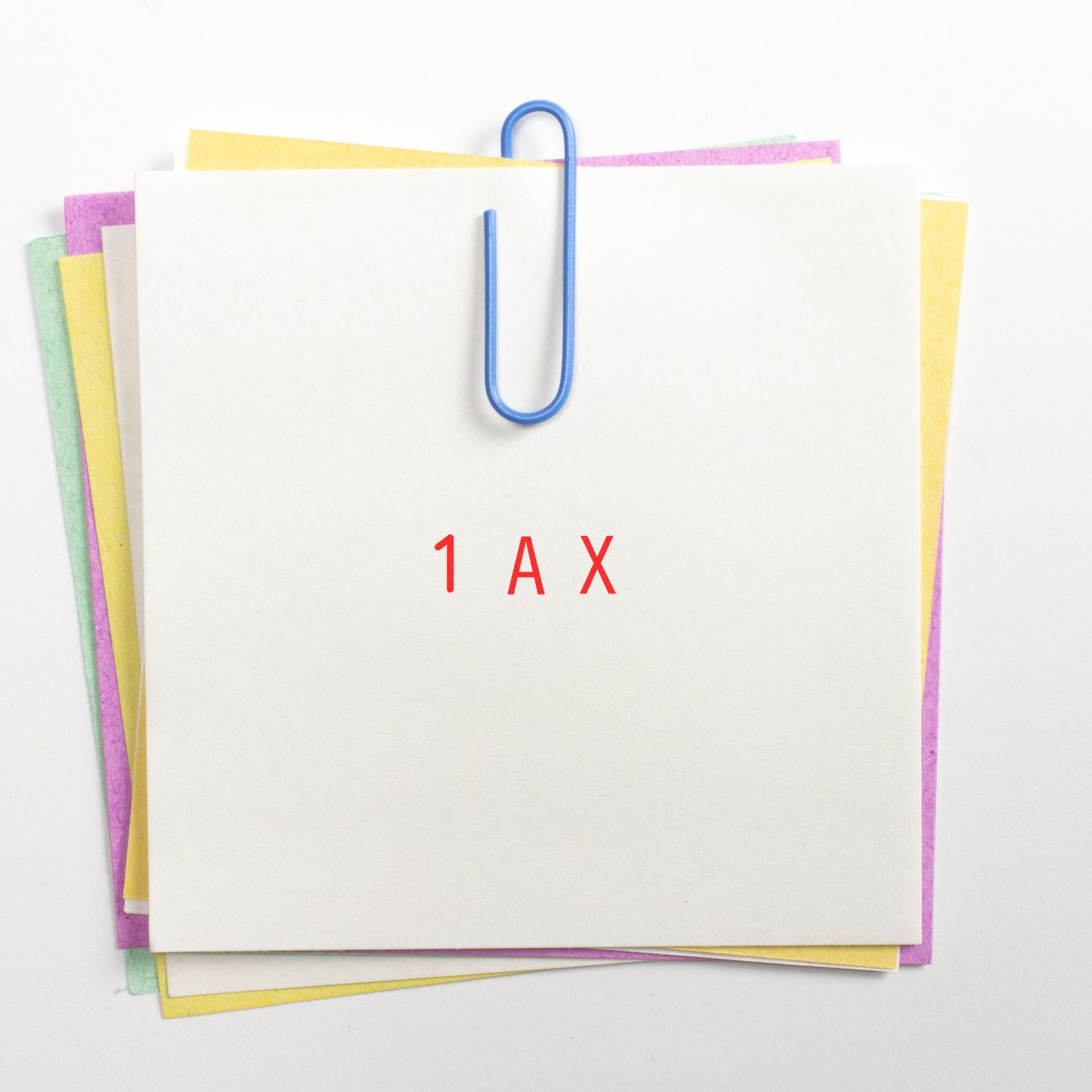 Stack of blank office papers clipped with a blue paperclip, labeled 1 AX, stationery background