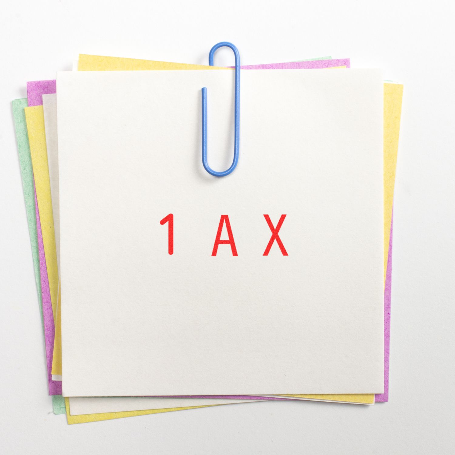 Stack of colorful office papers clipped together with a blue paperclip, featuring red 1AX text on white paper.