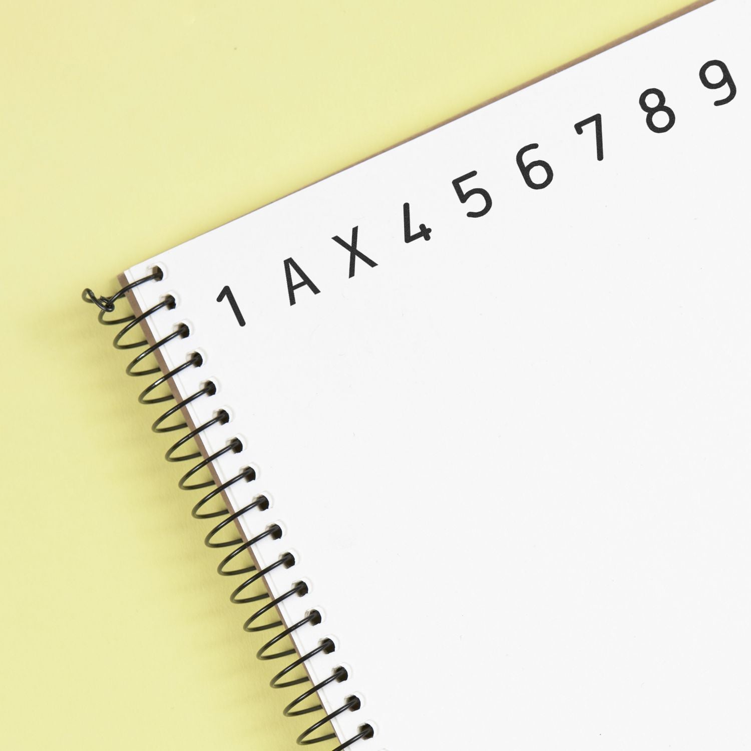 White spiral notebook with alphabet letters and numbers on a yellow background for education and learning.