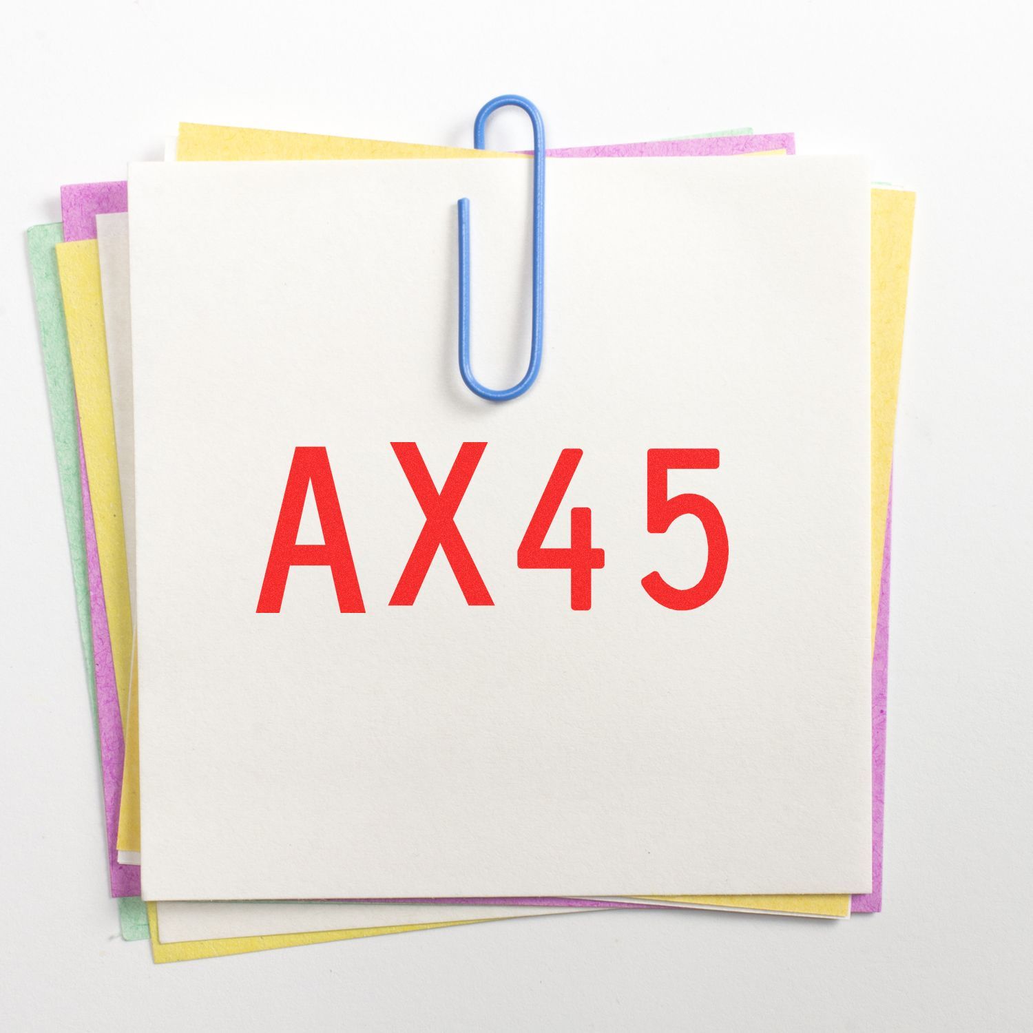 Stack of blank sticky notes clipped with a blue paperclip, labeled AX45 on white background