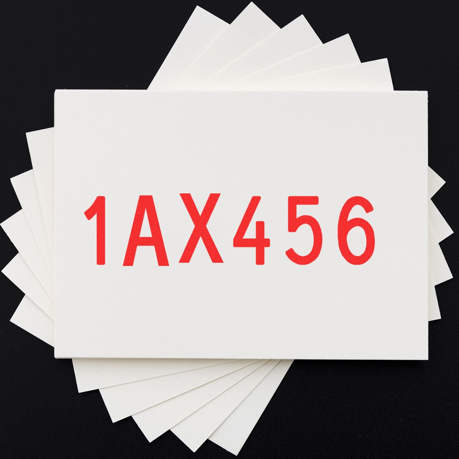 Stack of white paper sheets with red sample code 1AX456 on a black background.