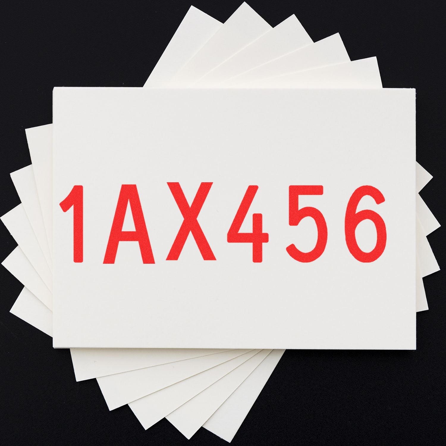 Stack of white paper cards with red 1AX456 printed on top against a black background