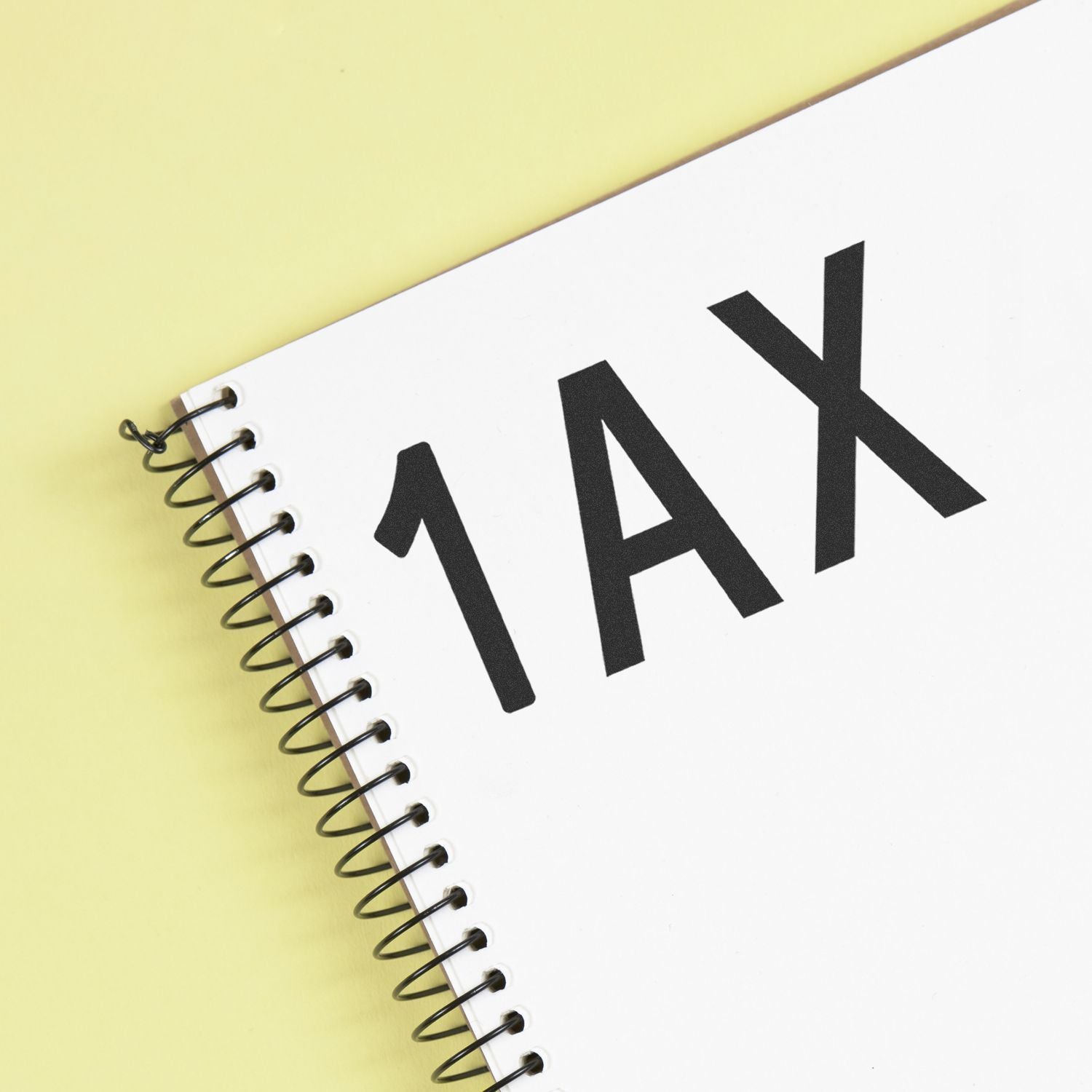 Spiral notebook with bold TAX text on a yellow background, representing tax planning and accounting.