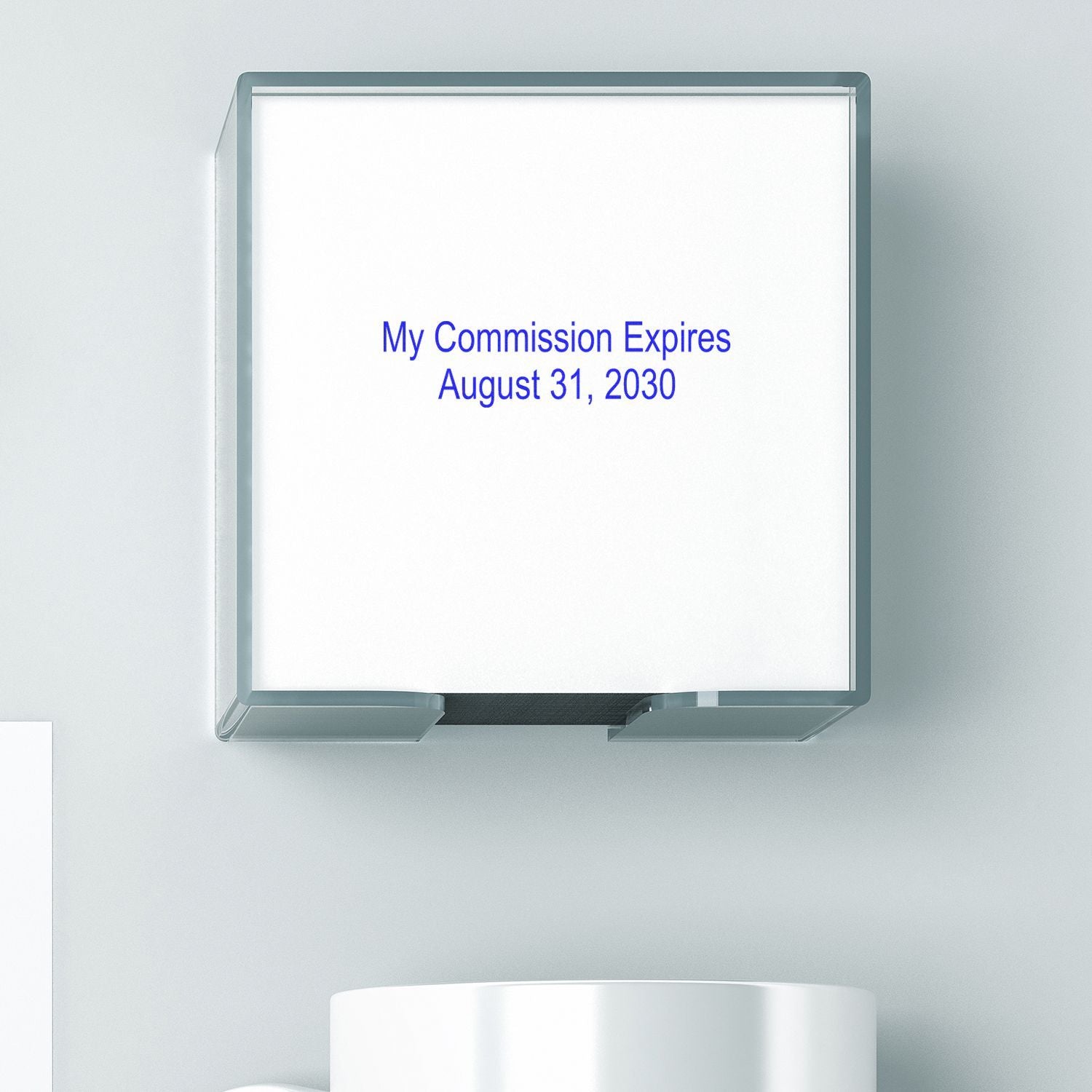 Wall-mounted sign with text My Commission Expires August 31, 2030 on a clean office wall.