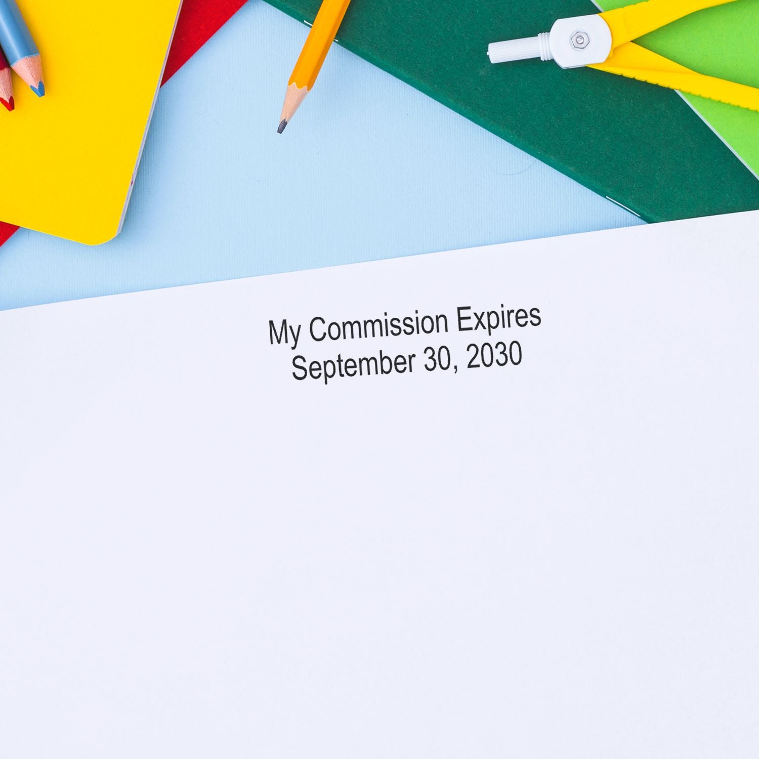 Colorful pencils and notebook with text reading My Commission Expires September 30, 2030 on a white page.