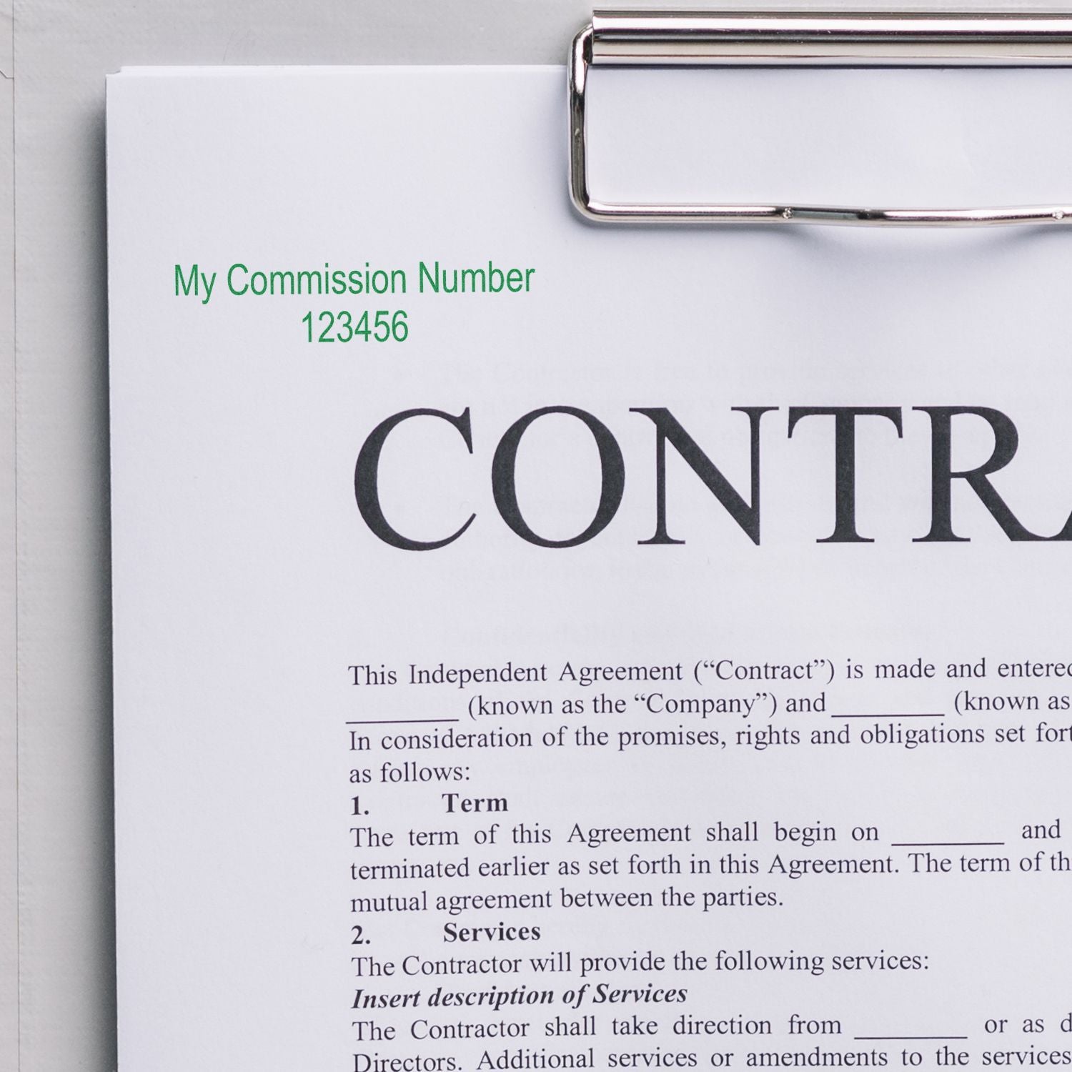 Independent contractor agreement contract with commission number clipped to clipboard, business legal document close-up.