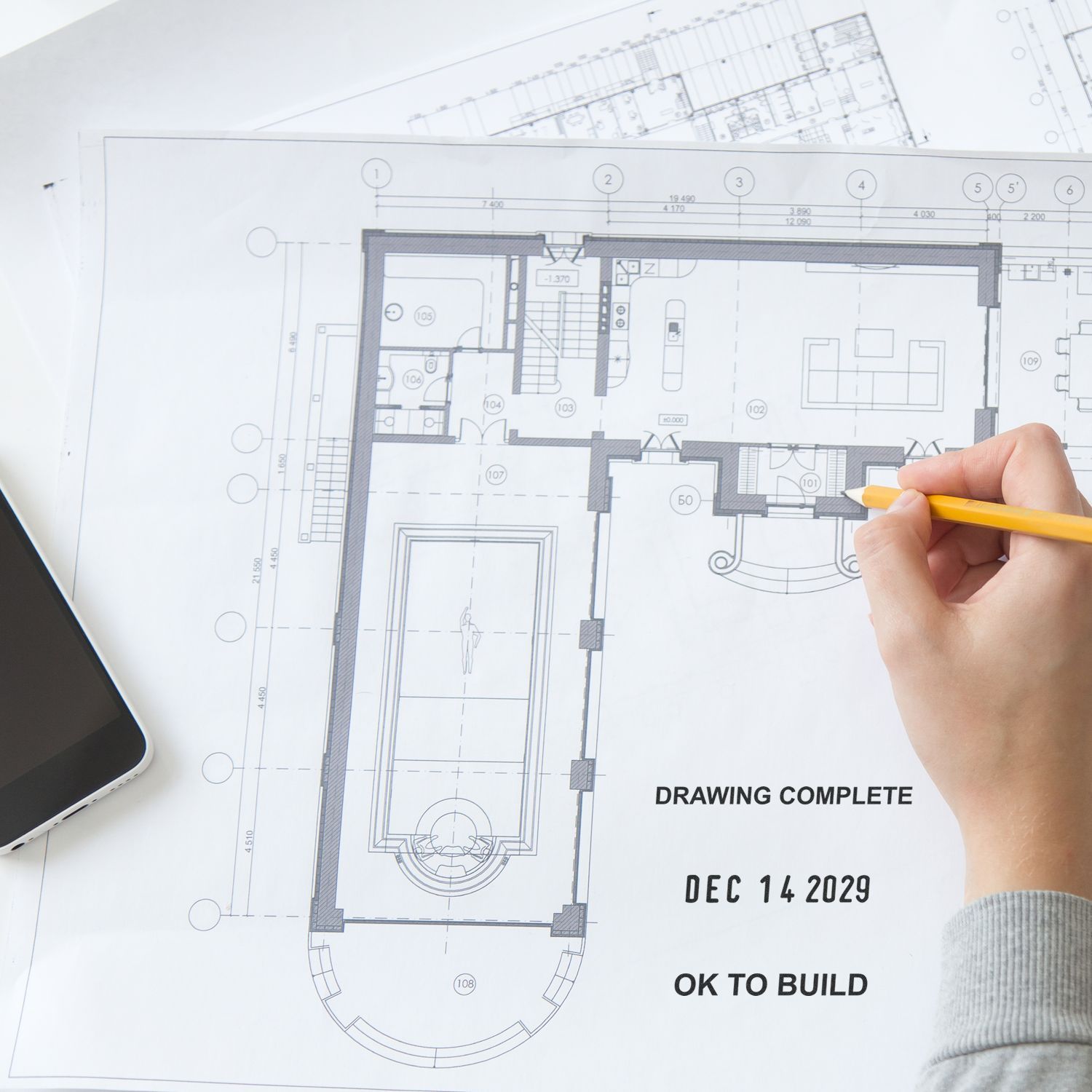 Hand drawing on an architectural blueprint floor plan with a pencil, marking a completed house design ready to build.
