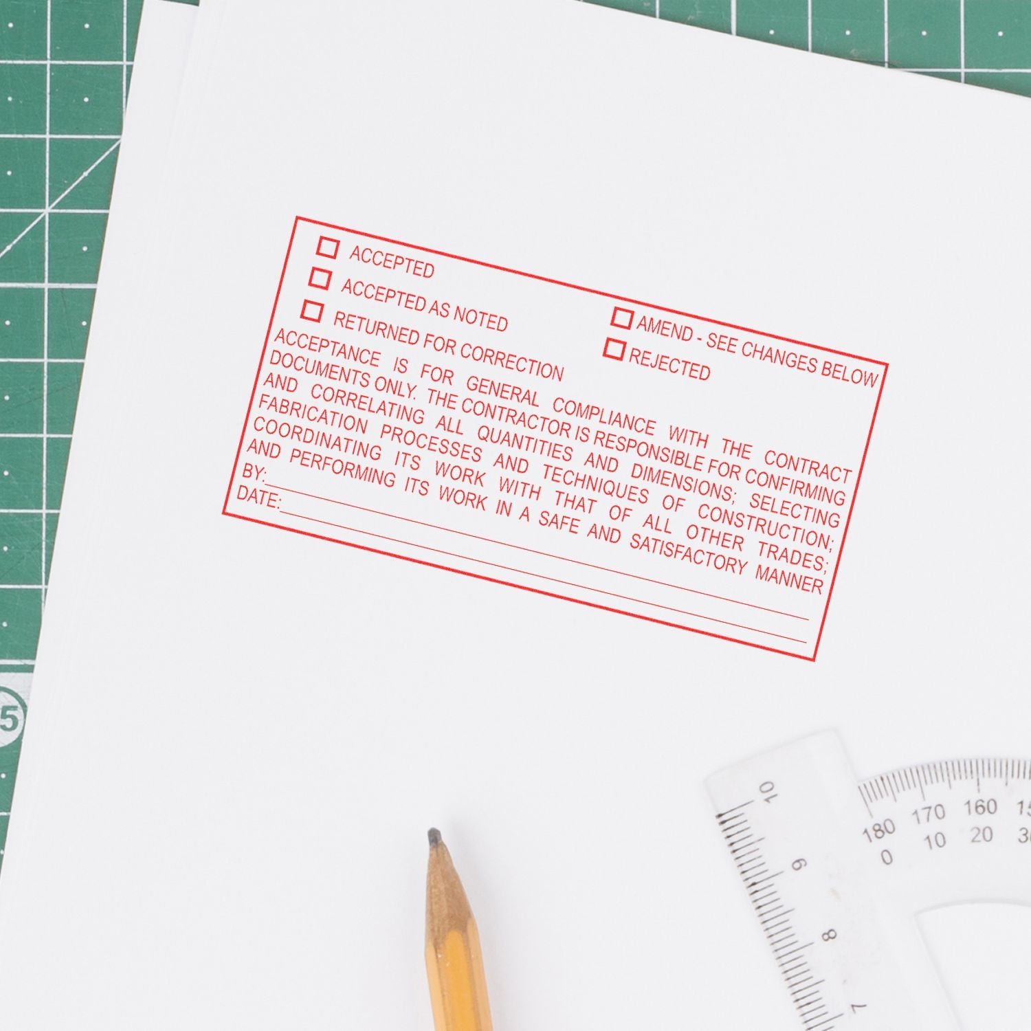 White document with red approval stamp, pencil, and ruler on a cutting mat for drafting and design review.