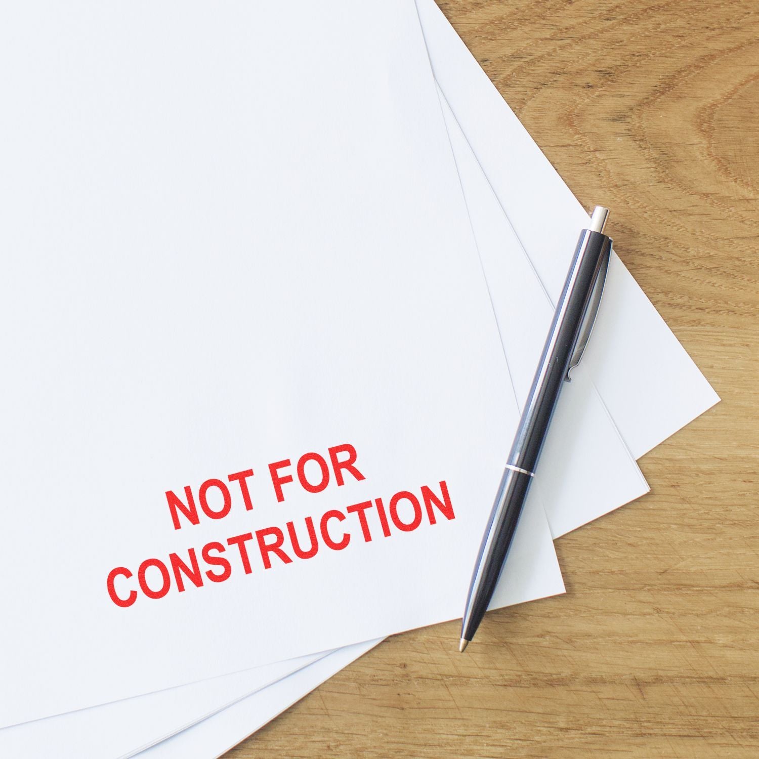 Not for construction stamped architectural plans with pen on wooden desk