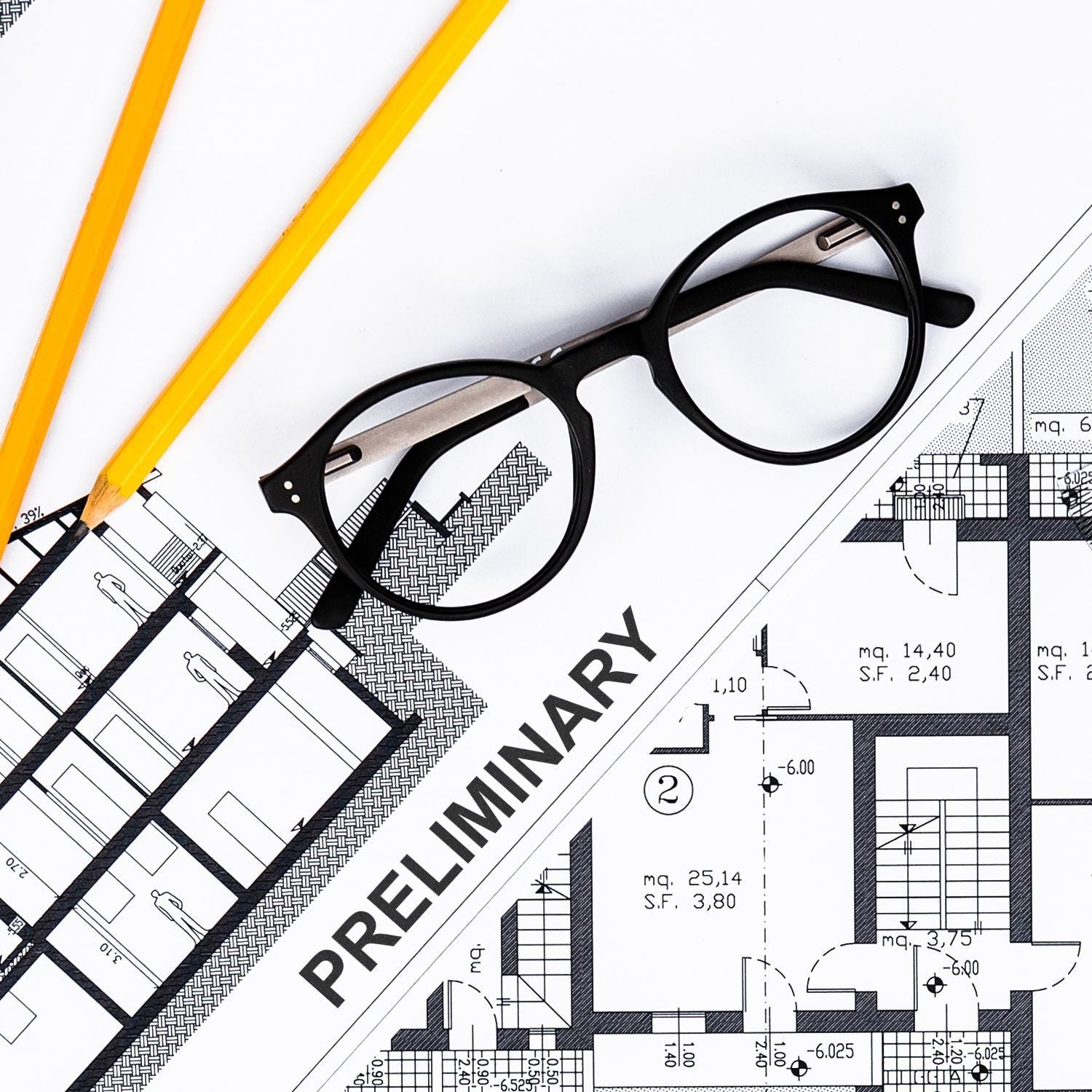 Black eyeglasses and yellow pencils on a preliminary architectural blueprint floor plan design concept.