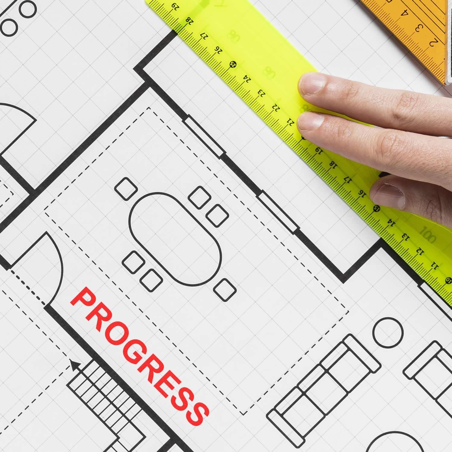 Hand measuring an architectural floor plan blueprint with a ruler and drafting tools, showing office layout progress.