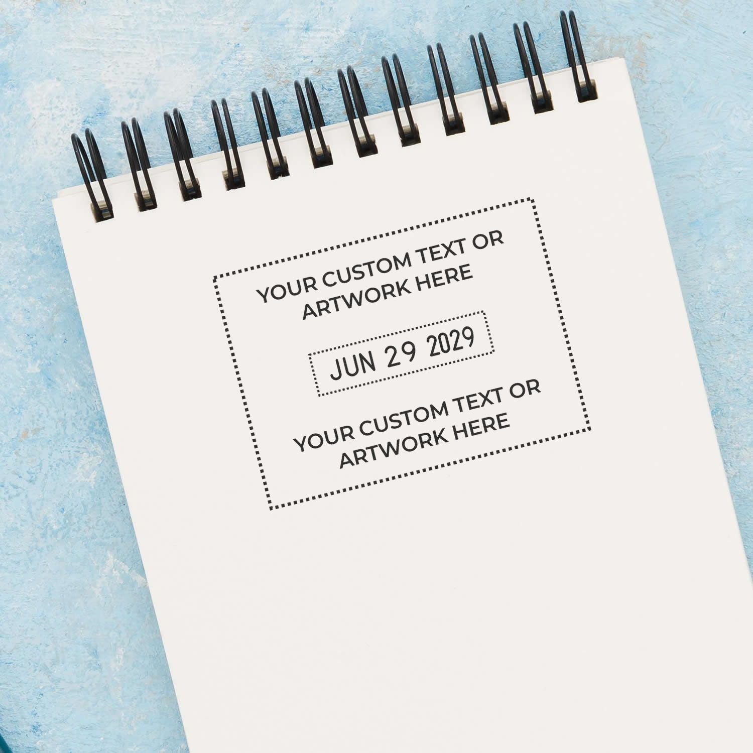 Blank spiral notebook mockup with custom text and date placeholder on blue textured background, ideal for branding and design presentation.