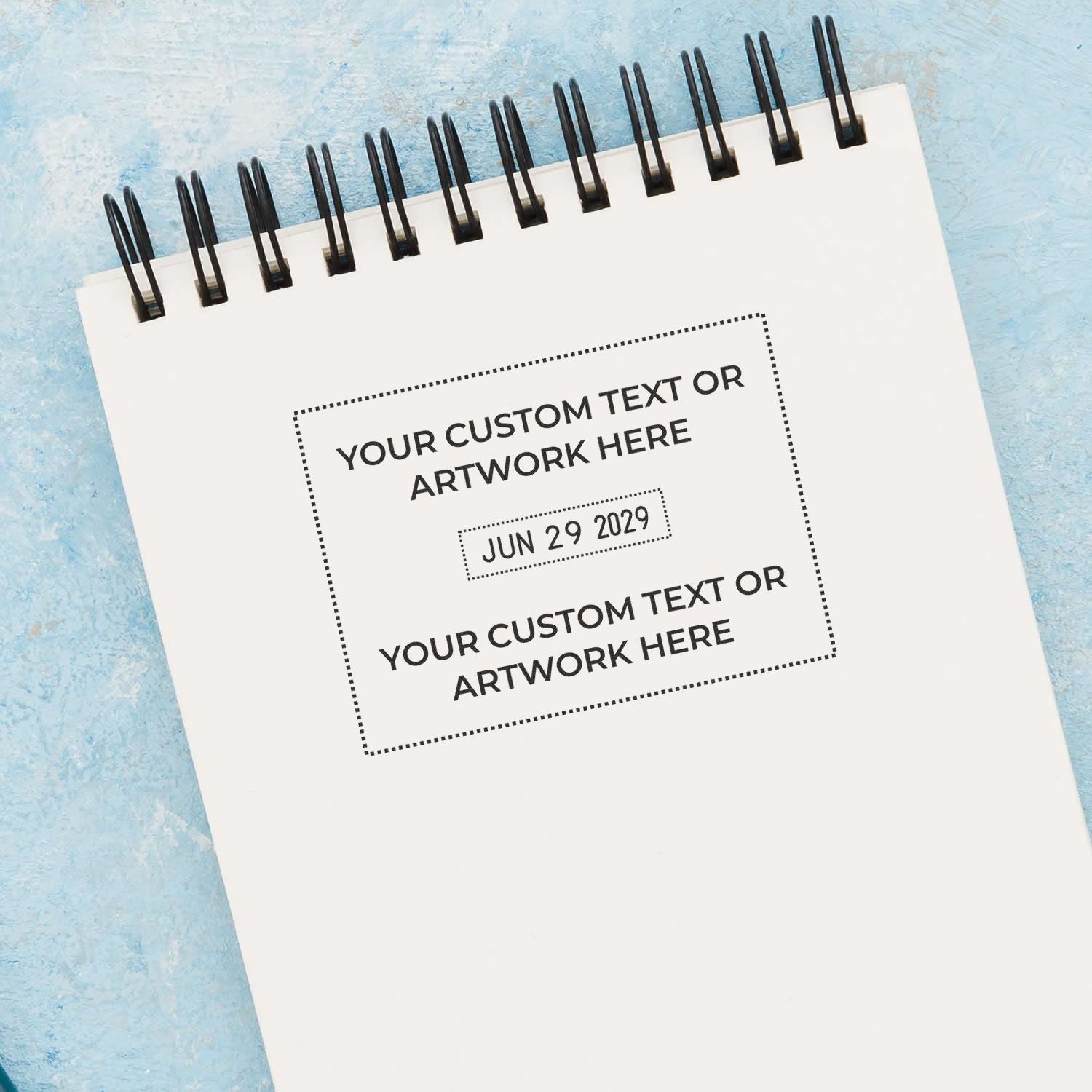 Blank spiral notebook mockup with customizable text and date on a blue textured background