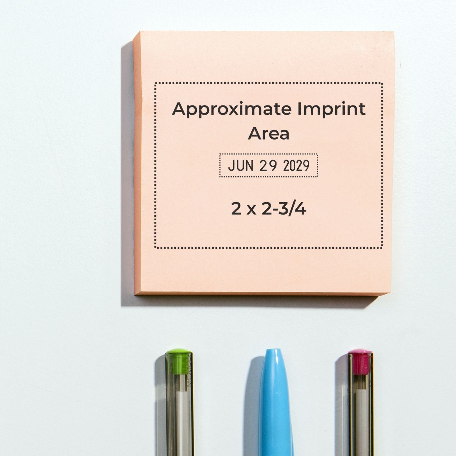 Peach square sticky note mockup with approximate imprint area and pens on a white background.