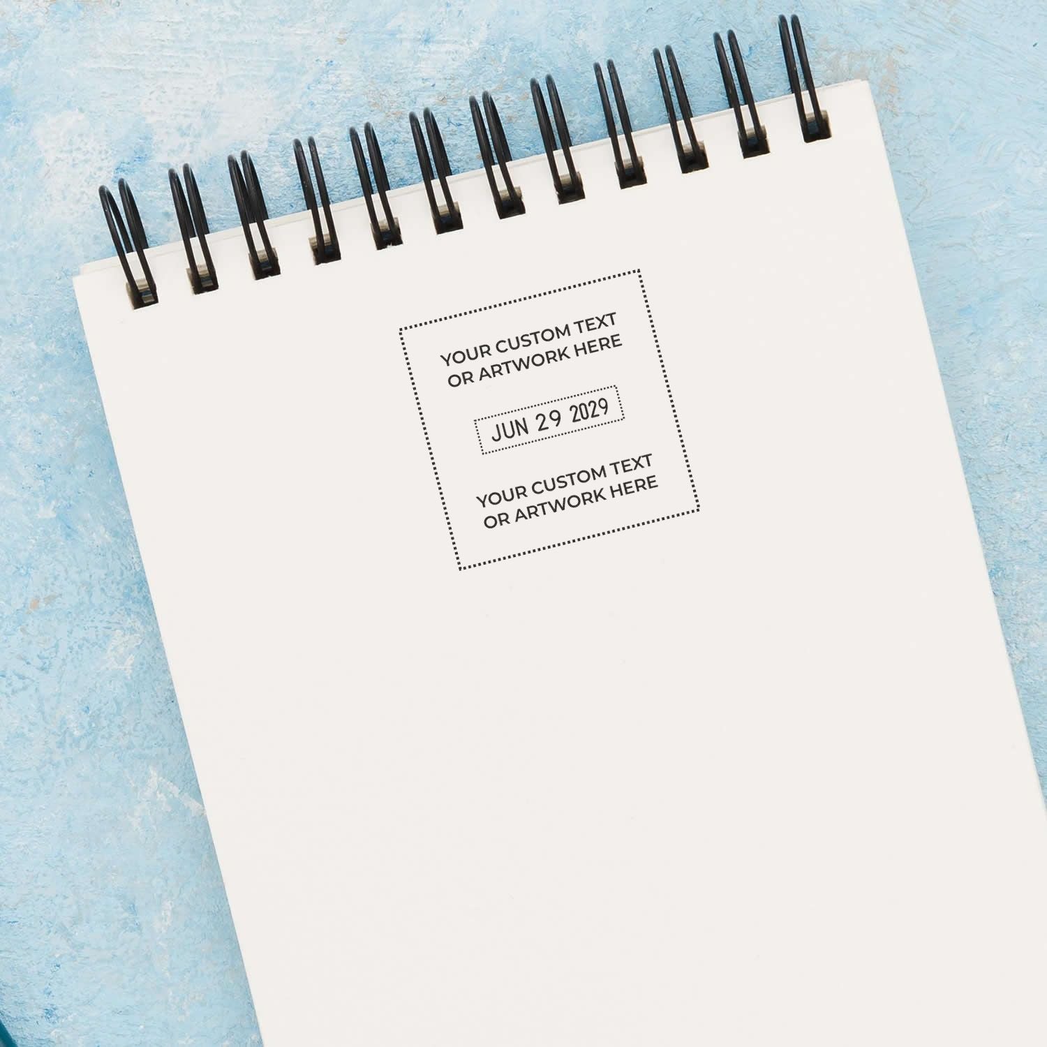 Blank spiral notebook mockup with customizable cover text on a blue textured background, ideal for calendar, planner, or stationery design.