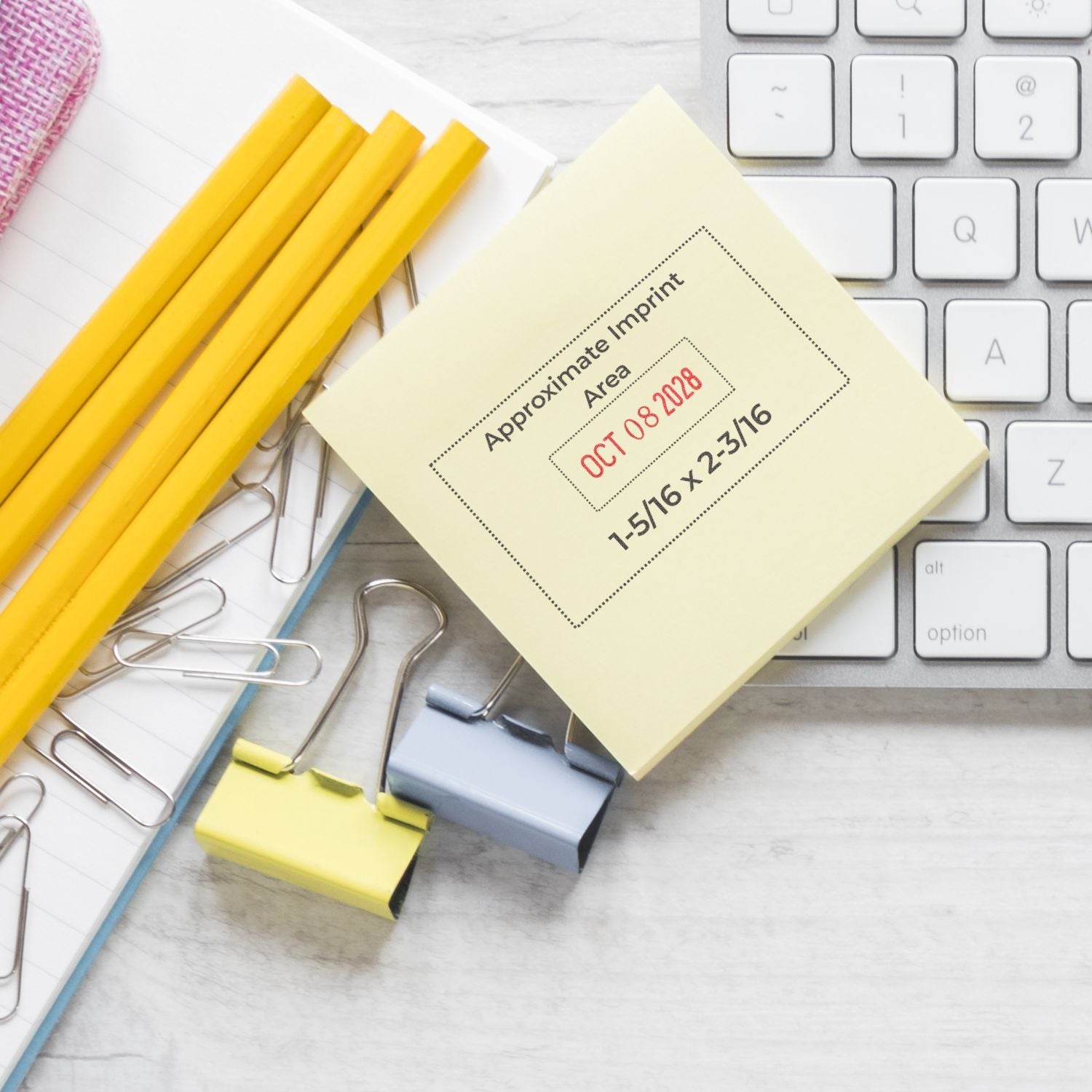 Office desk flat lay with keyboard, sticky notes, yellow pencils, and paper clips for workspace organization.