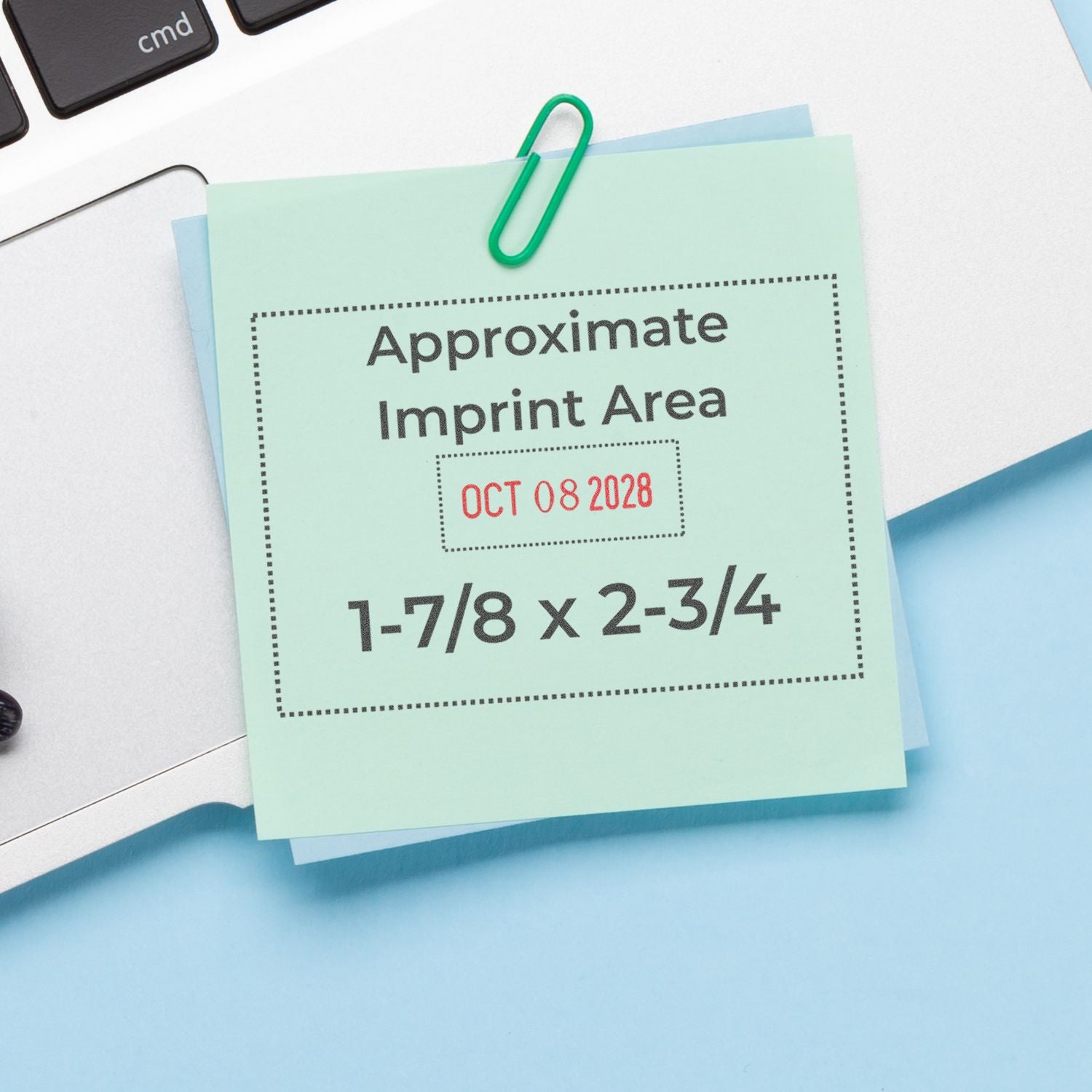 Sticky note showing approximate imprint area for custom stamp, 1-7/8 x 2-3/4 inches, clipped to a laptop keyboard.