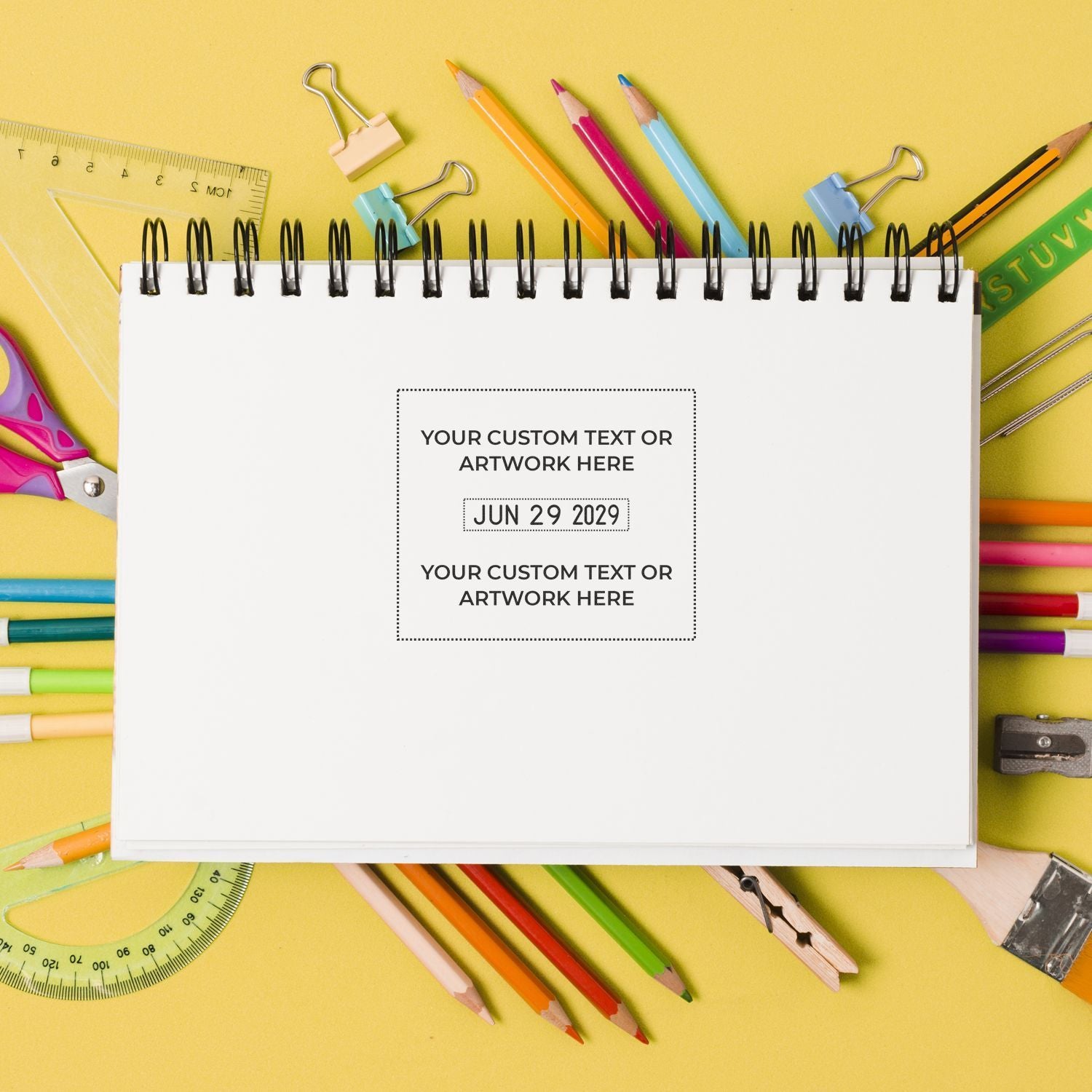 Blank spiral notebook mockup surrounded by colorful school supplies on a yellow background, ideal for back-to-school design or custom stationery branding.