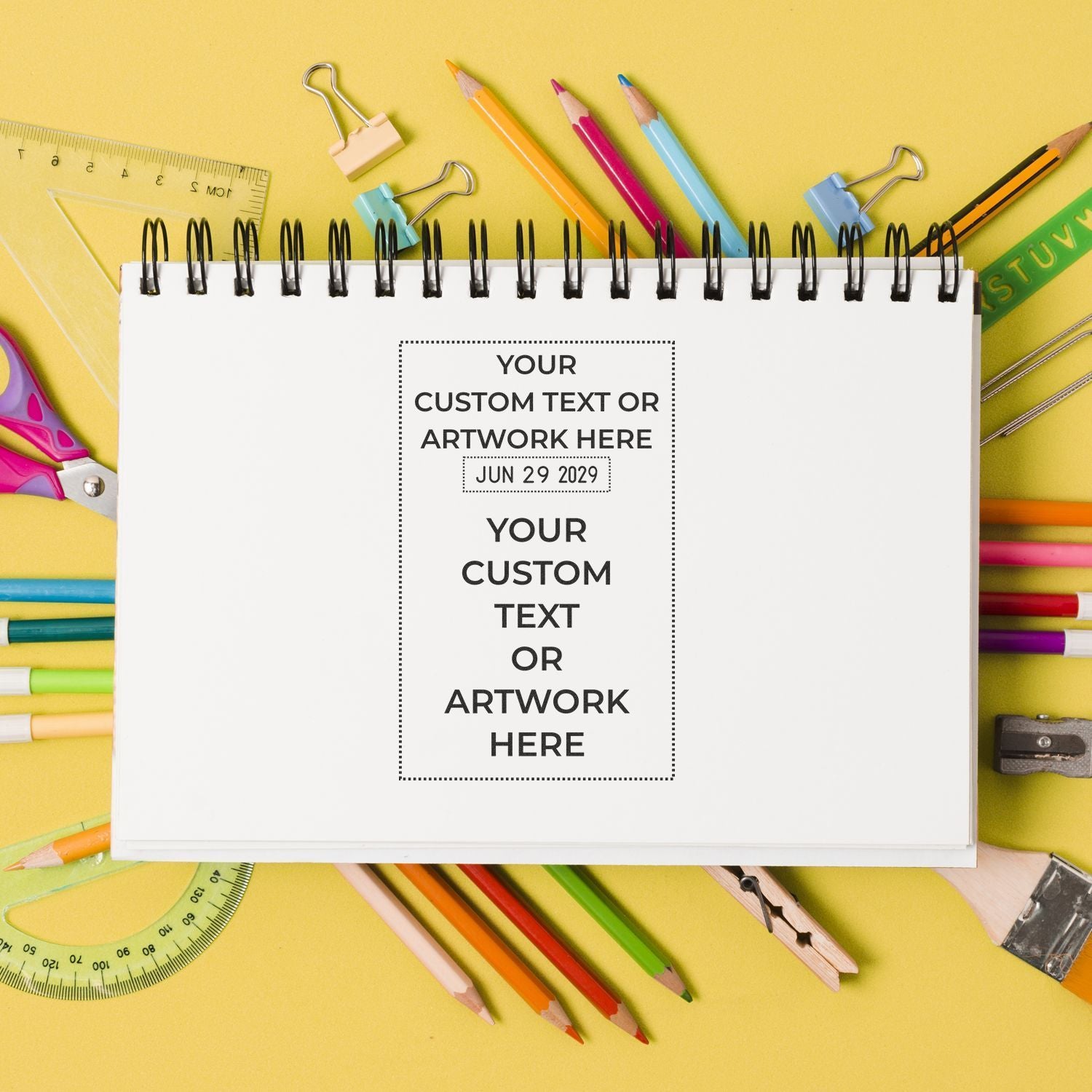 Blank spiral notebook with colorful school supplies on yellow background, customizable text template for back-to-school stationery or planner cover.
