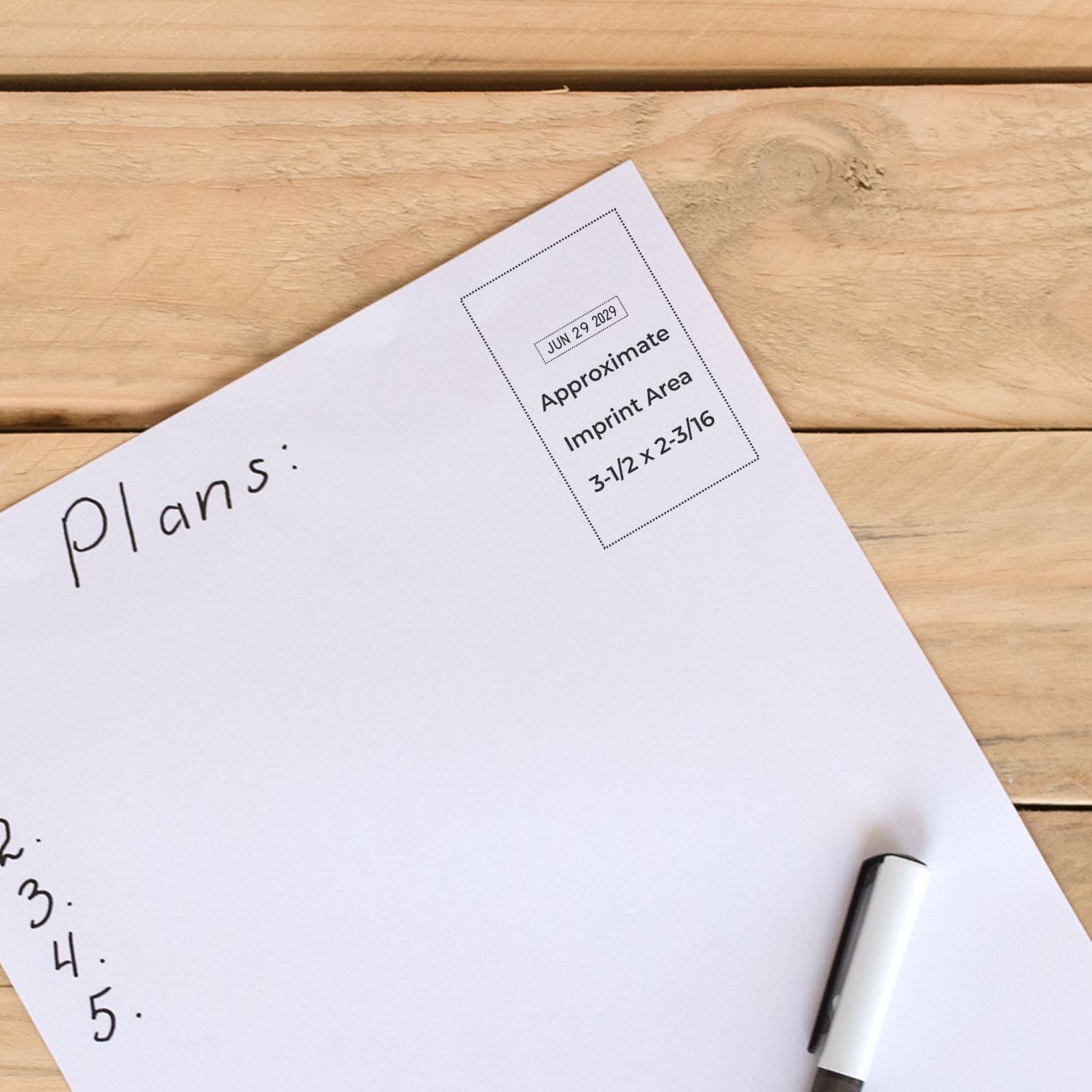 Handwritten plans on a white paper notebook page with a pen on a wooden desk, minimal workspace flat lay.